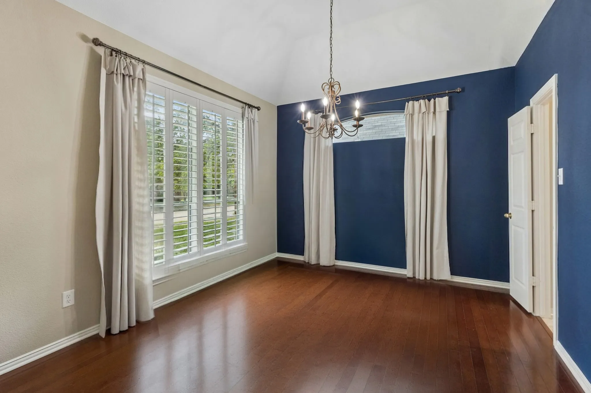 The spacious dining room allows for large gatherings to celebrate a meal or enjoy game night. Room boasts plantation shutters and hardwood flooring.