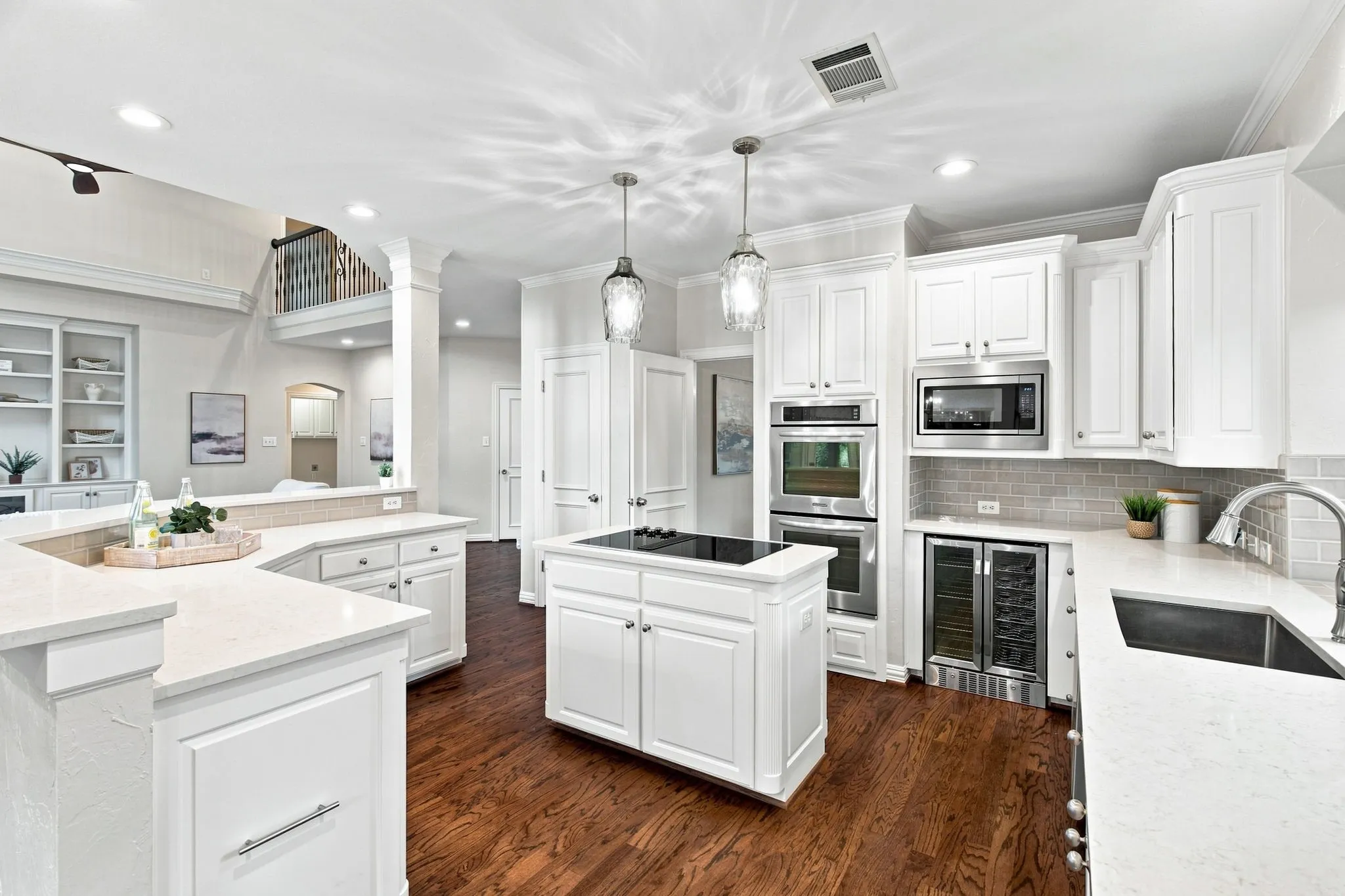 Spacious kitchen featuring white cabinetry, light countertops, wood-finish flooring, stainless steel appliances, and a built-in beverage cooler