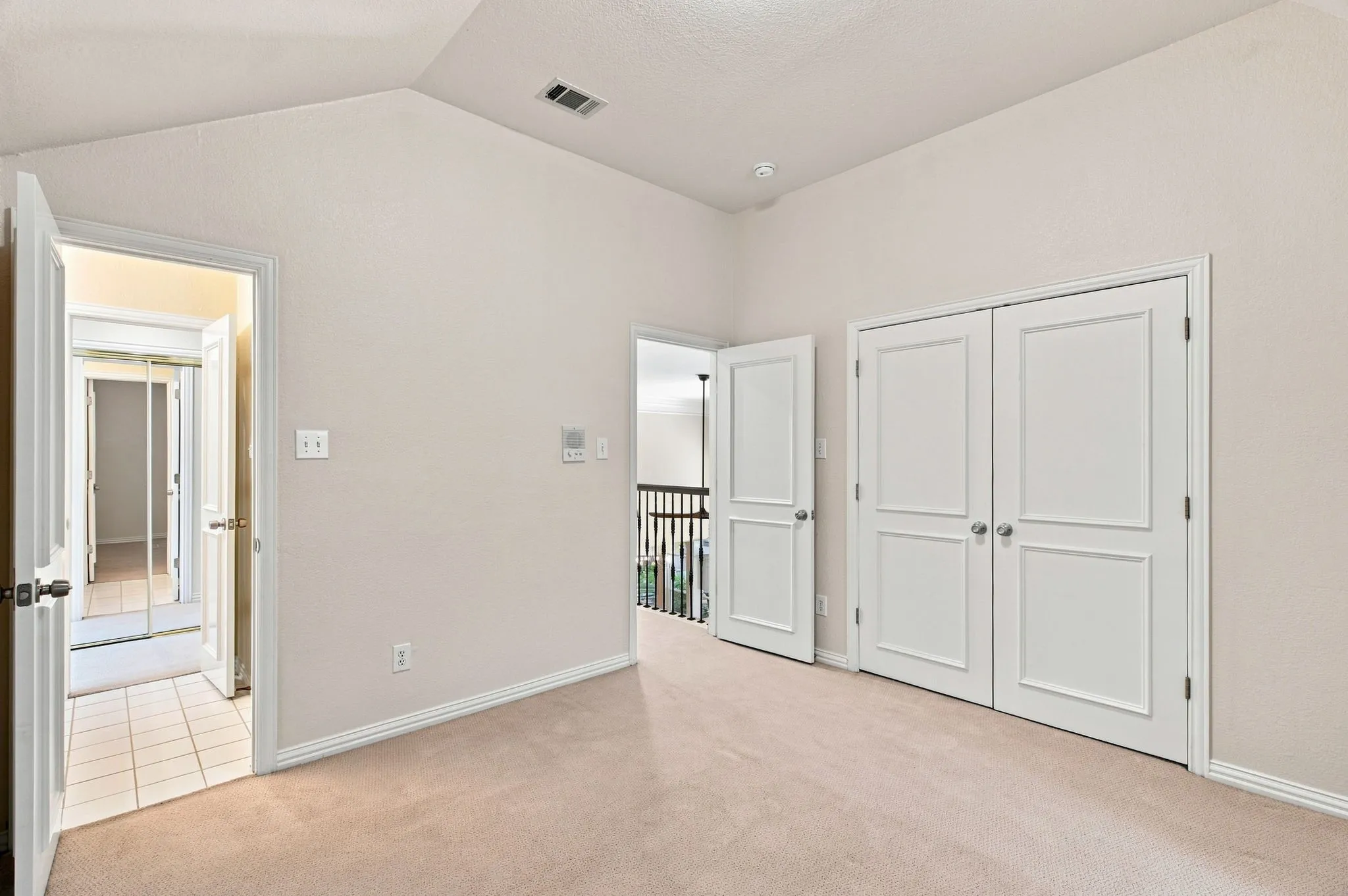 Vaulted ceiling, neutral tone walls, white trim, carpeted flooring, and white paneled doors