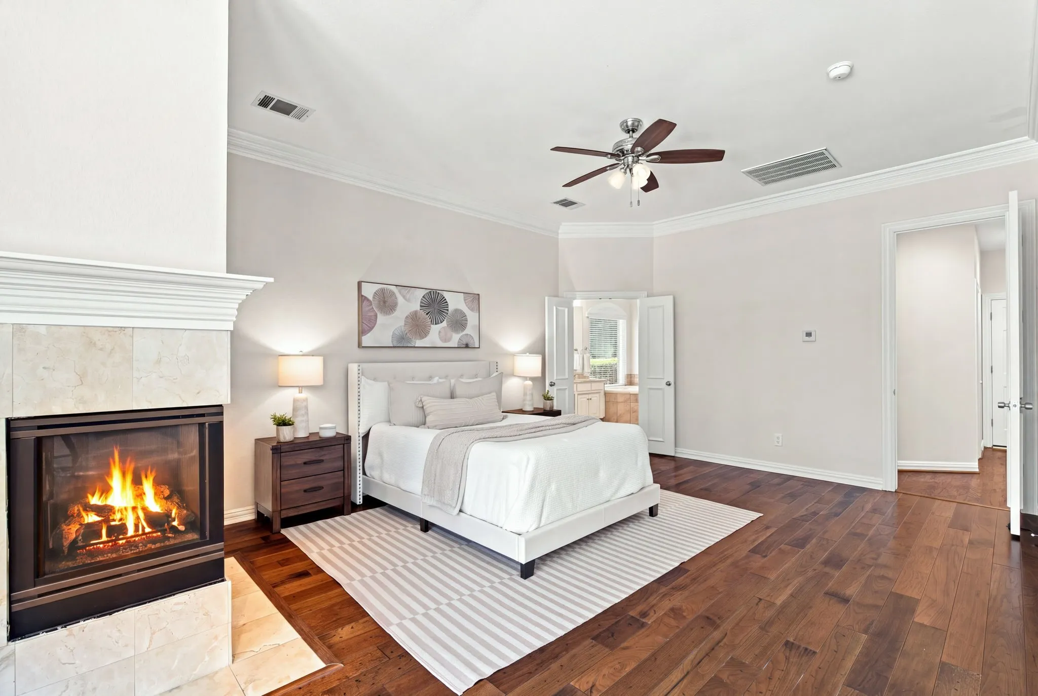 Hardwood flooring, vaulted ceiling, crown molding, stone-surround fireplace, and ceiling fan