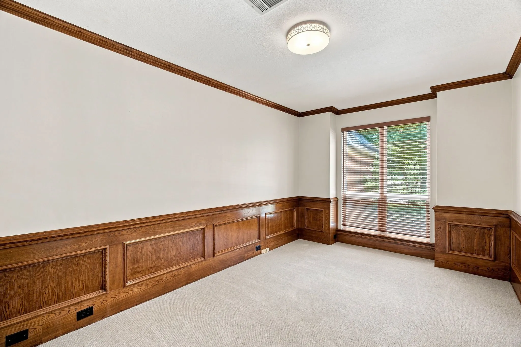 Neutral-toned carpeting, wood paneling, wood trim, and a built-in window with blinds
