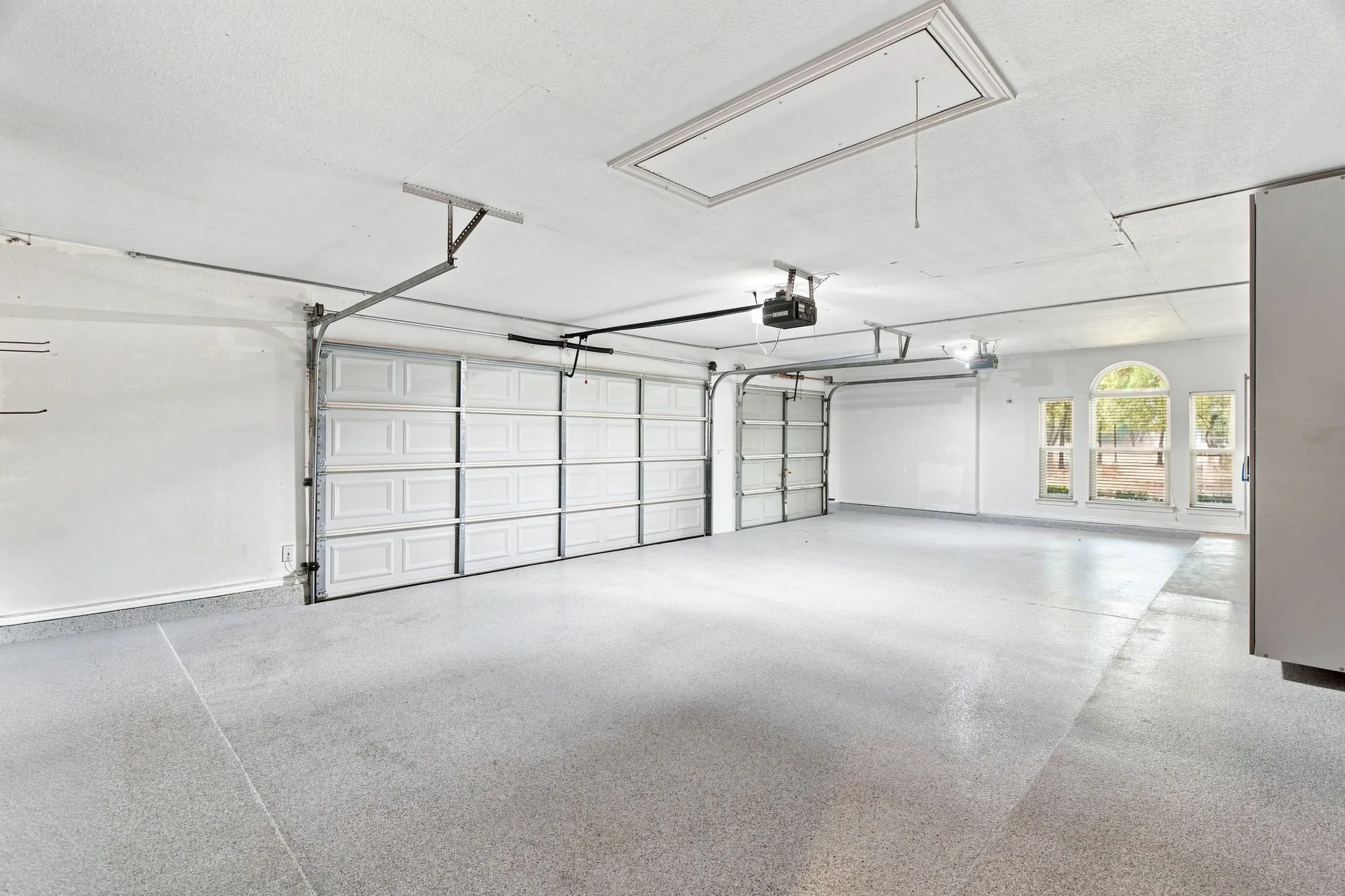 Three-car garage with an epoxy-coated floor, two automatic garage doors, and arched windows