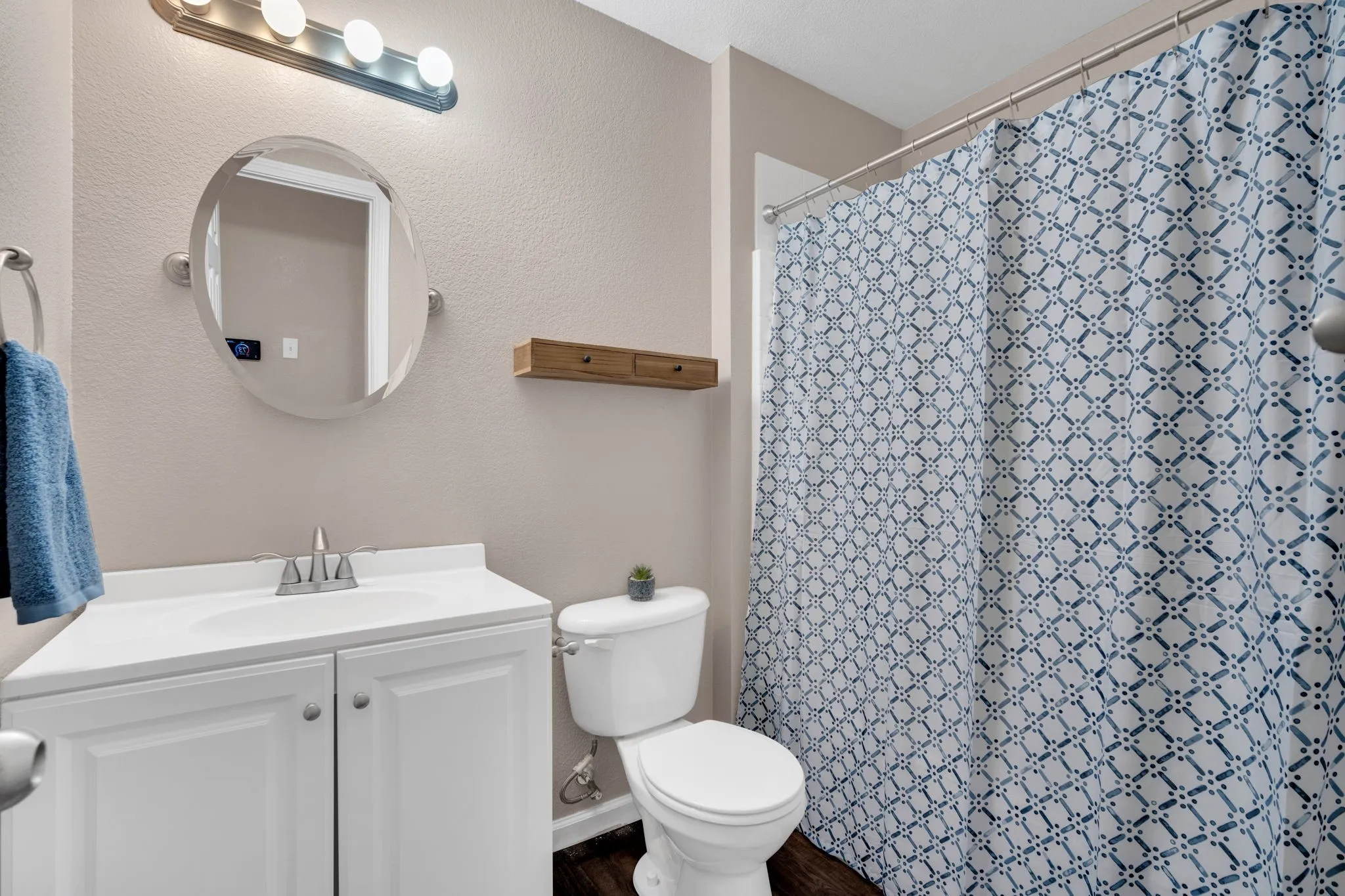 Secondary bathroom featuring a white vanity with a single basin, an oval mirror, and a full shower enclosure