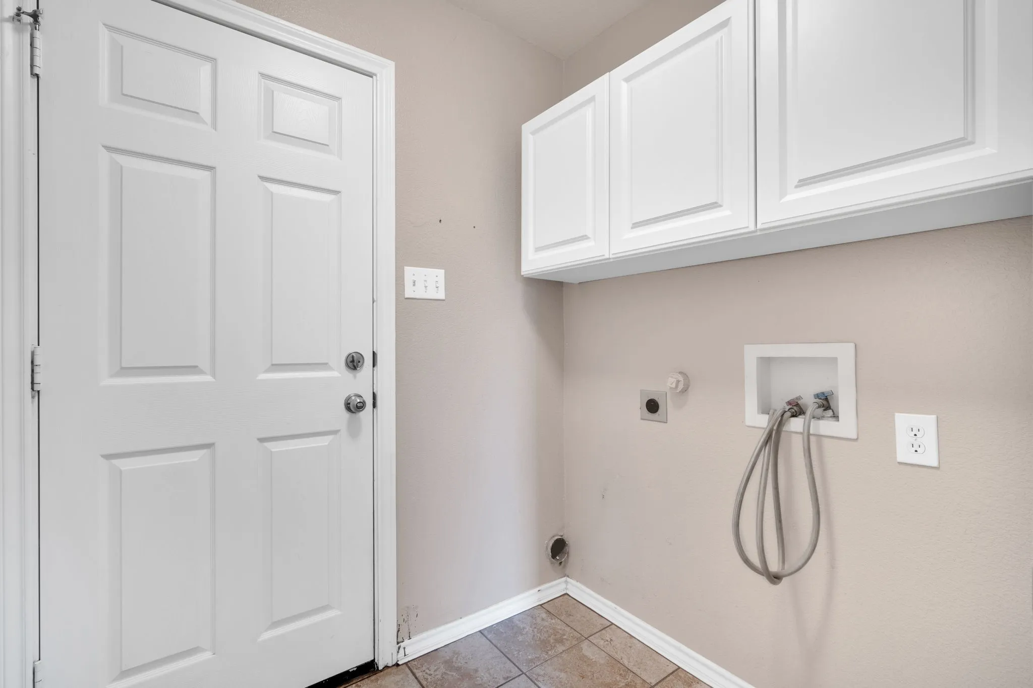Laundry area featuring overhead white cabinetry and tile flooring
