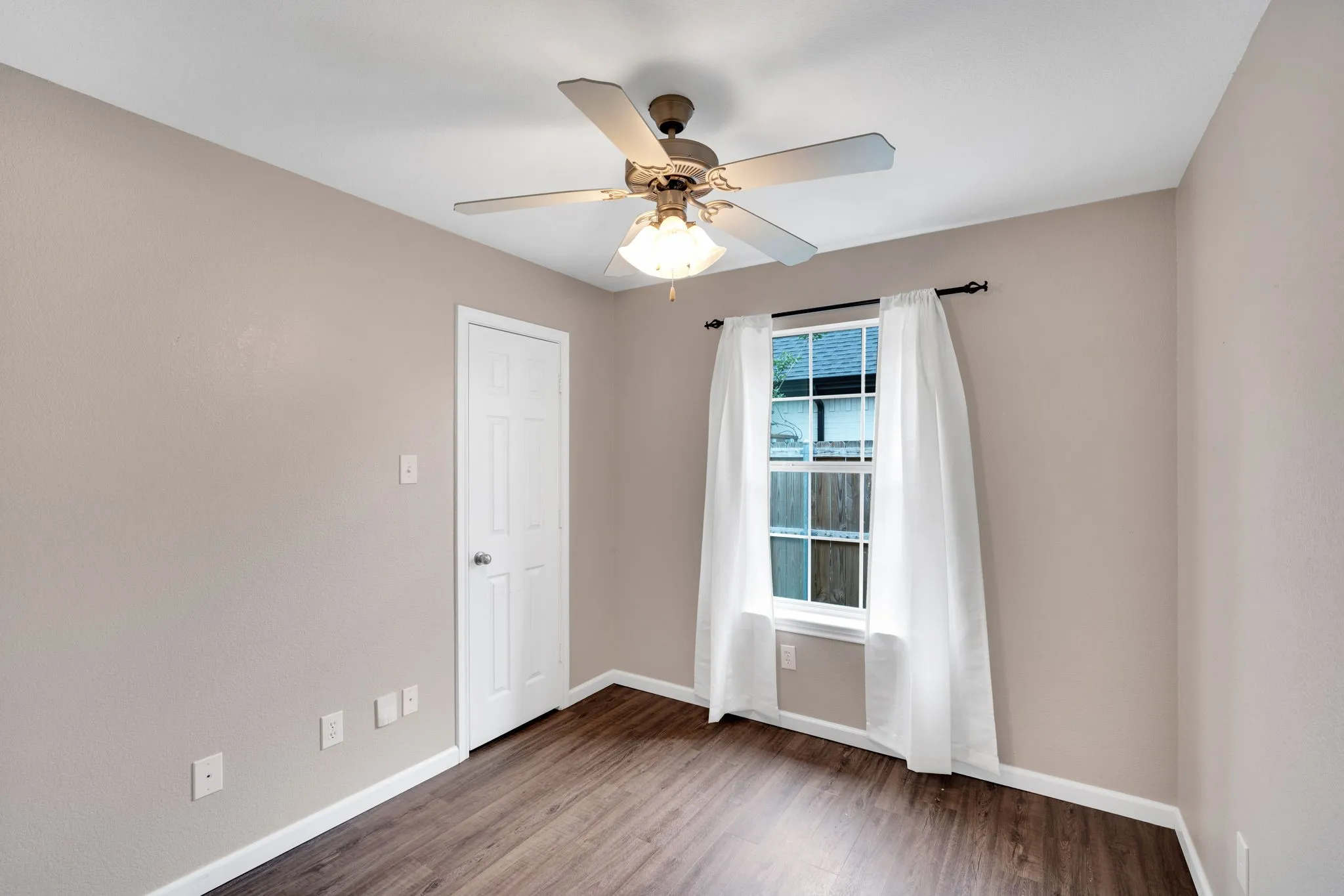 Bedroom featuring wood-finish flooring, a ceiling fan with light fixture, and a double-hung window with white trim