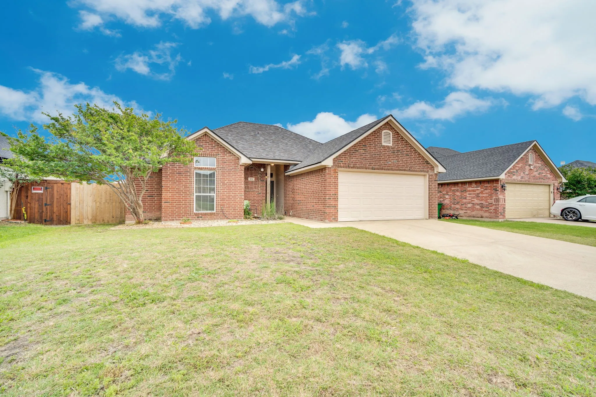 Brick exterior with a dark shingle roof, an attached garage, and a concrete driveway