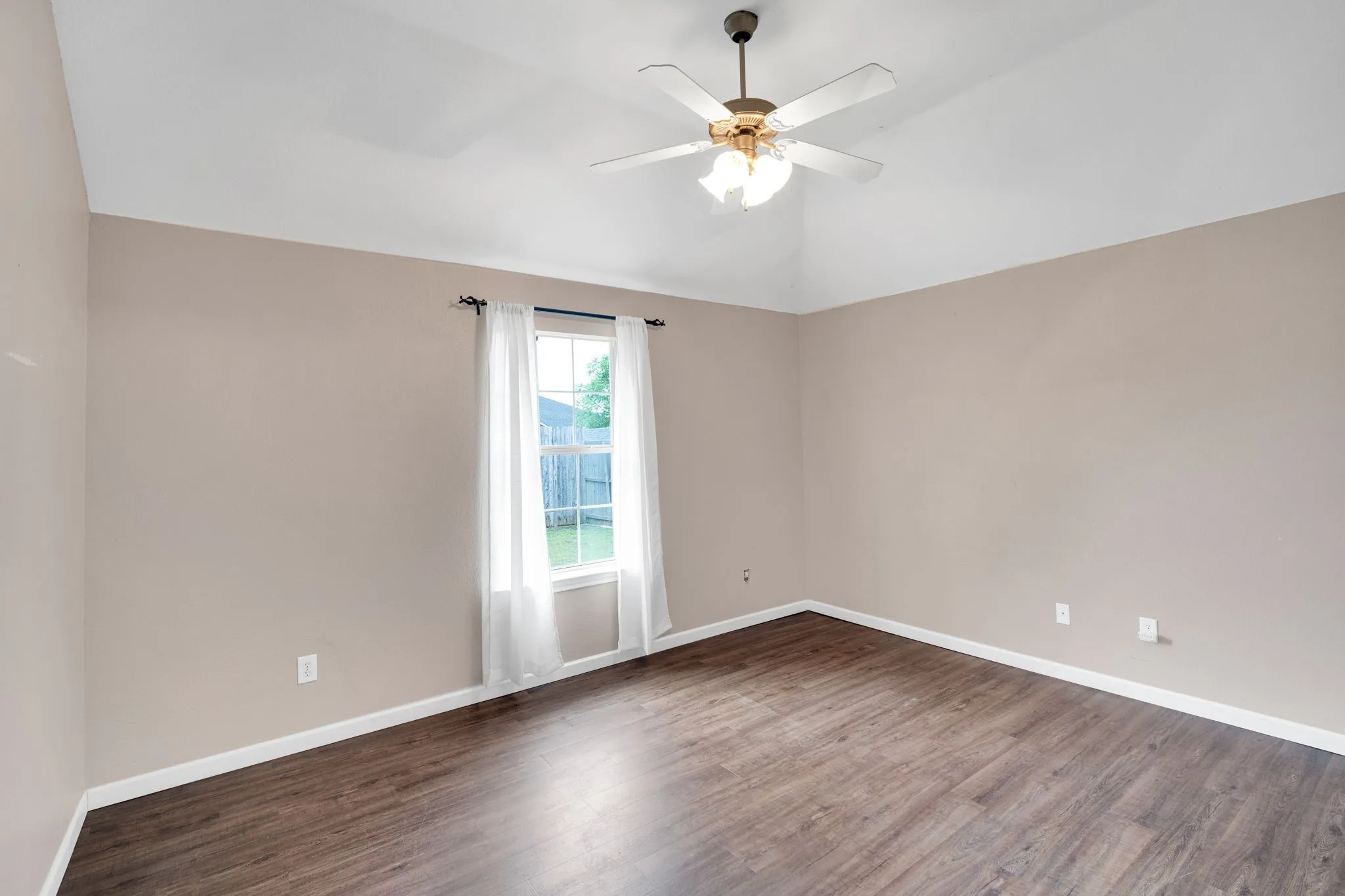 Spacious Primary Bedroom featuring vaulted ceilings, wood-finish flooring, a contemporary ceiling fan with lighting, and a window with white trim