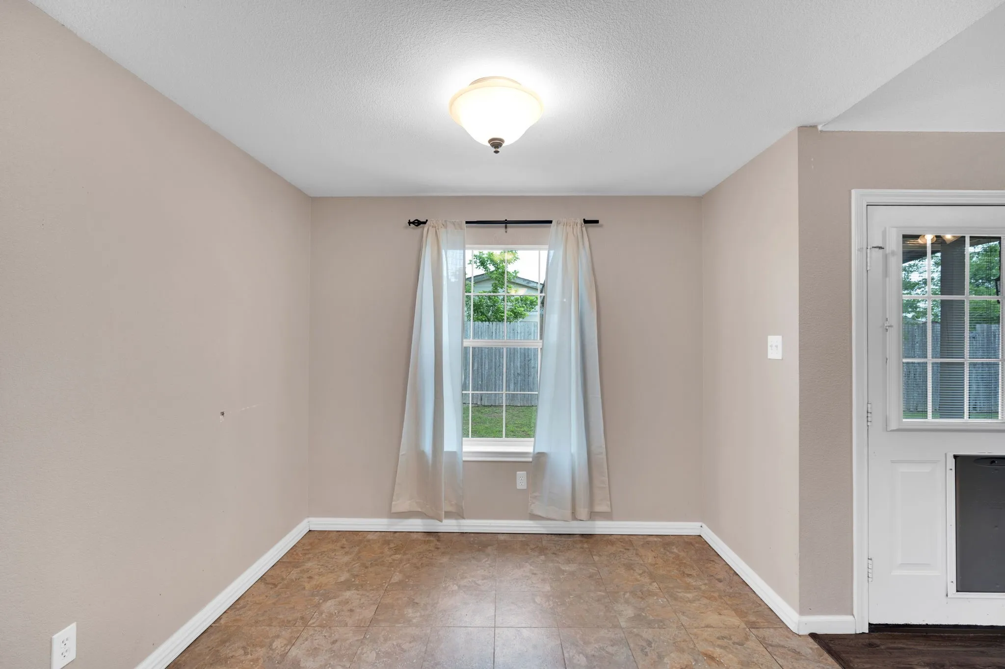 Interior room featuring a single window, overhead lighting, and resilient flooring