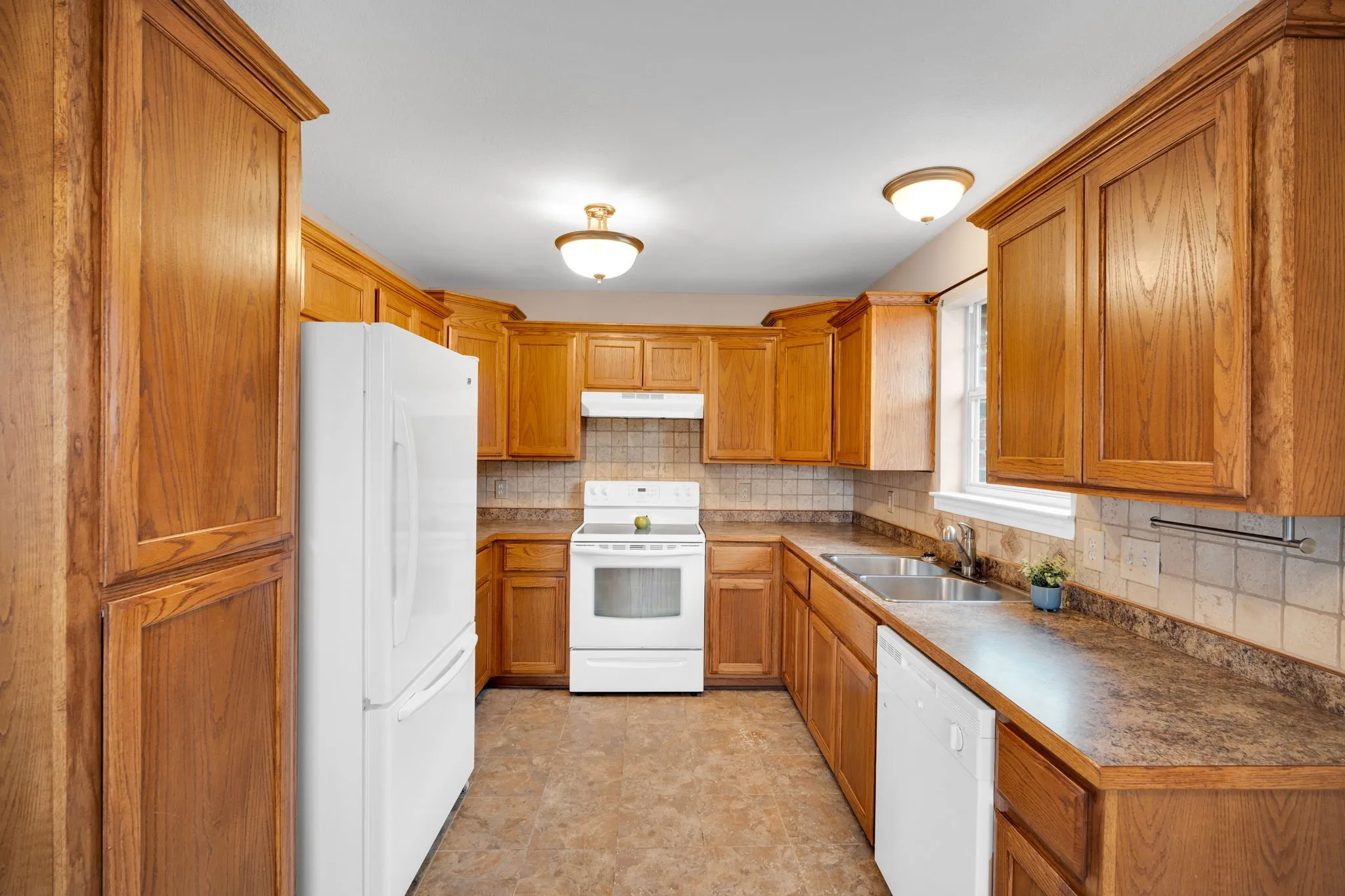 U-shaped kitchen featuring wood cabinetry, white appliances, laminate countertops, and tile backsplash
