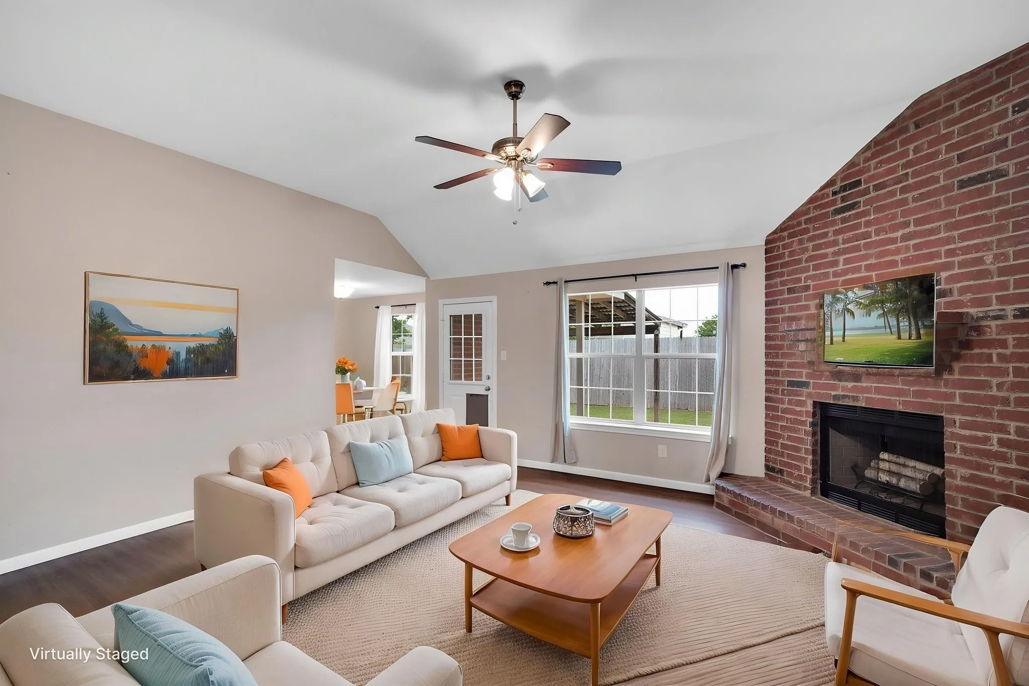Spacious living area featuring a brick fireplace, vaulted ceiling, wood-finish flooring, and a ceiling fan