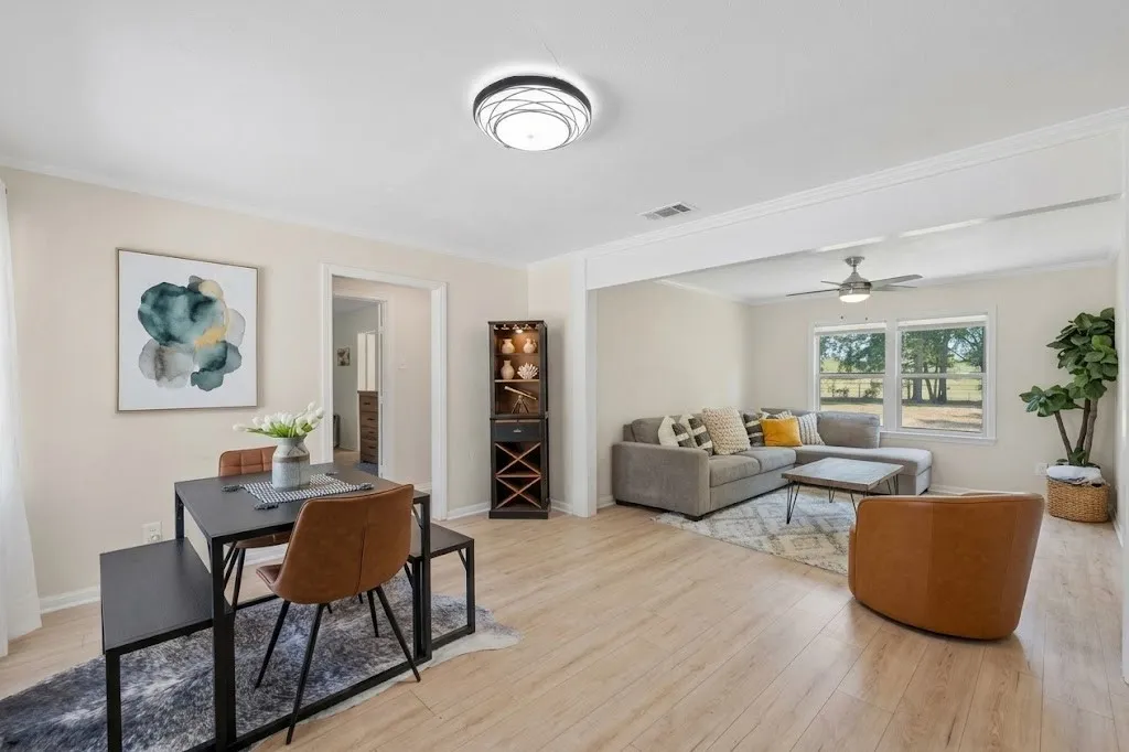 Open-concept living space with light wood-finish flooring, a contemporary ceiling light fixture, and a built-in corner cabinet
