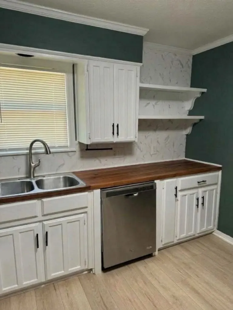 Kitchen featuring white shaker-style cabinetry, wood-finish countertops, and a stainless steel dishwasher
