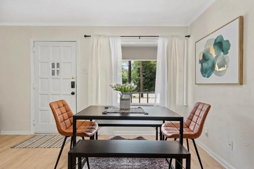 Recessed window with white curtains, wood-finish flooring, white paneled door with glass inserts, and white wall finishes