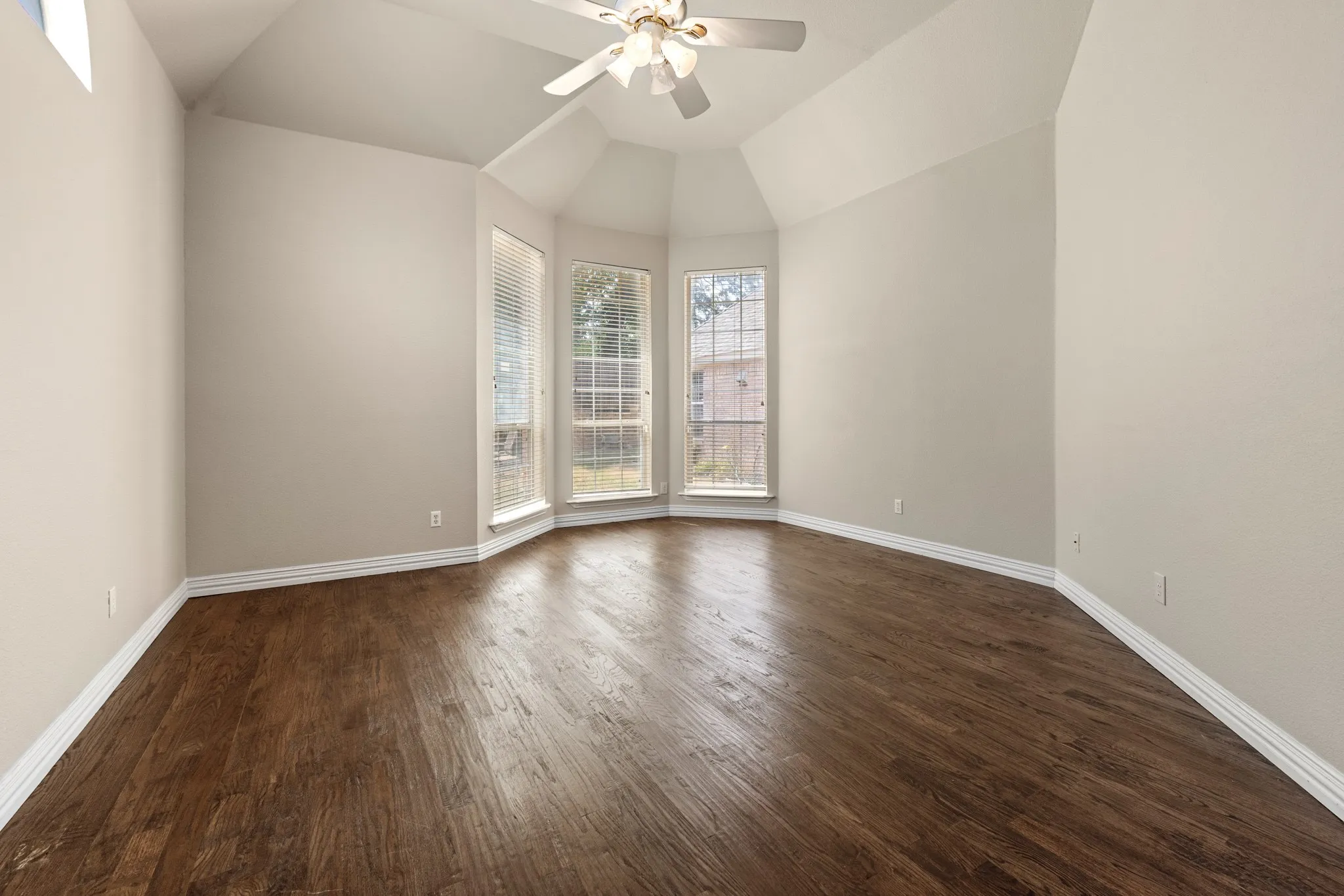 Primary bedroom with dark hardwood / wood-style floors and ceiling fan