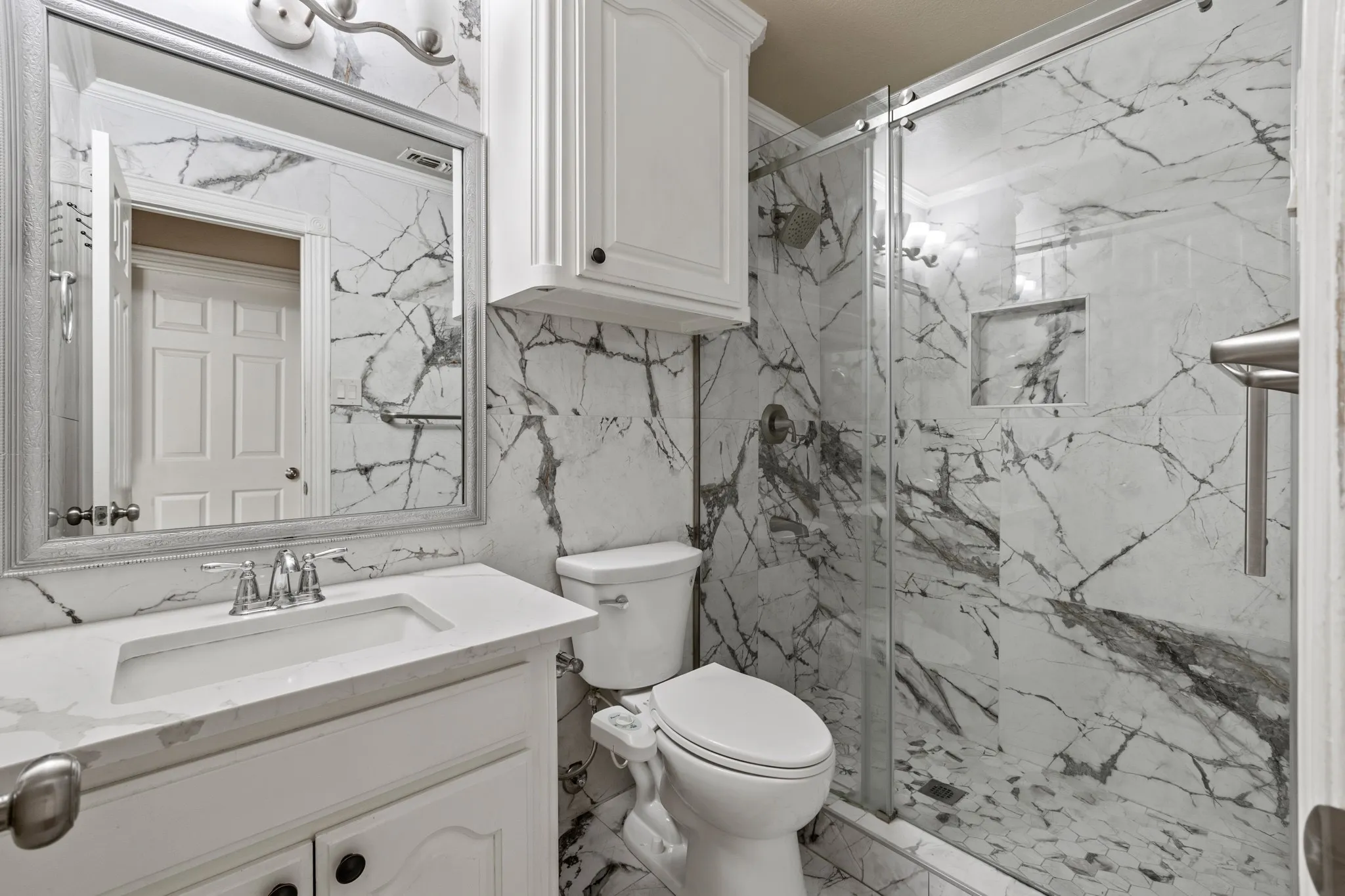 Bathroom with tile flooring, a shower with shower door, tile walls, vanity with extensive cabinet space, and toilet