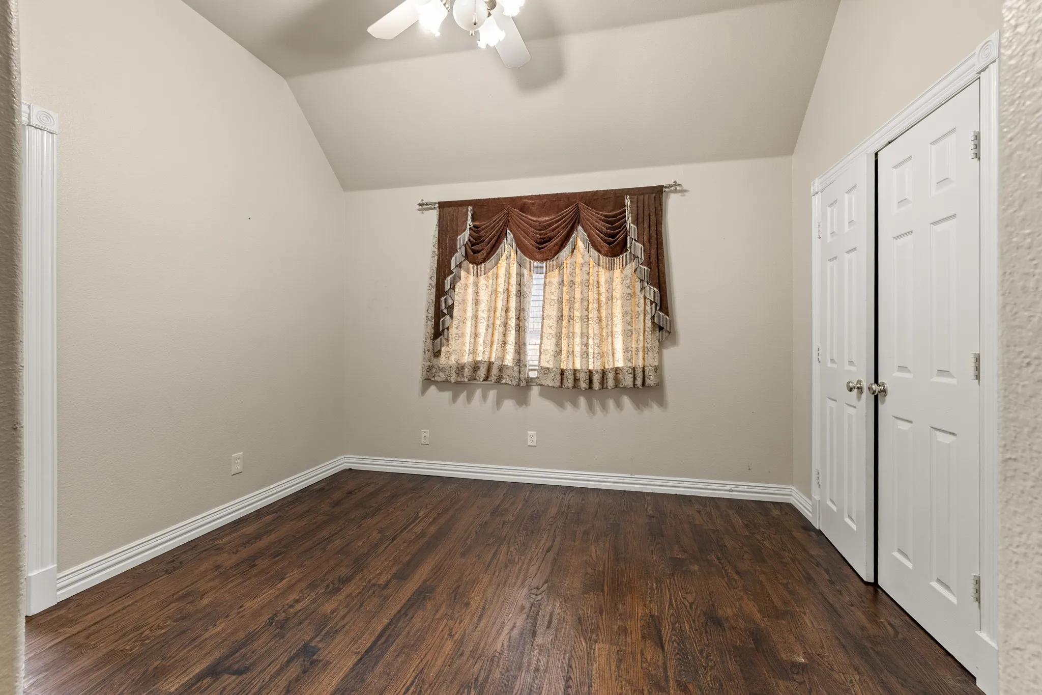 Unfurnished bedroom with wood-type flooring, ceiling fan, and lofted ceiling