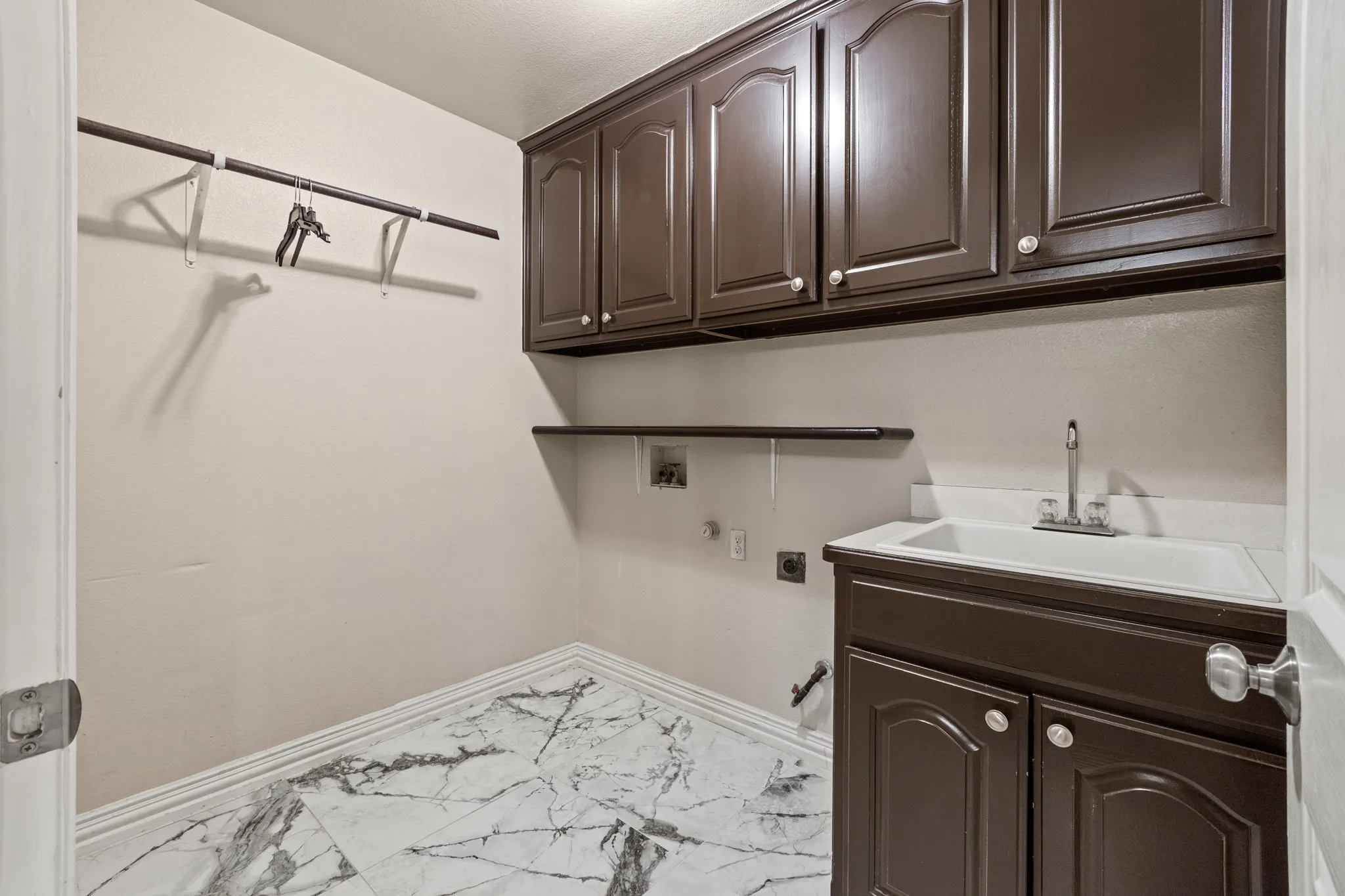 Laundry area featuring hookup for a washing machine, light tile flooring, hookup for an electric dryer, sink, and cabinets