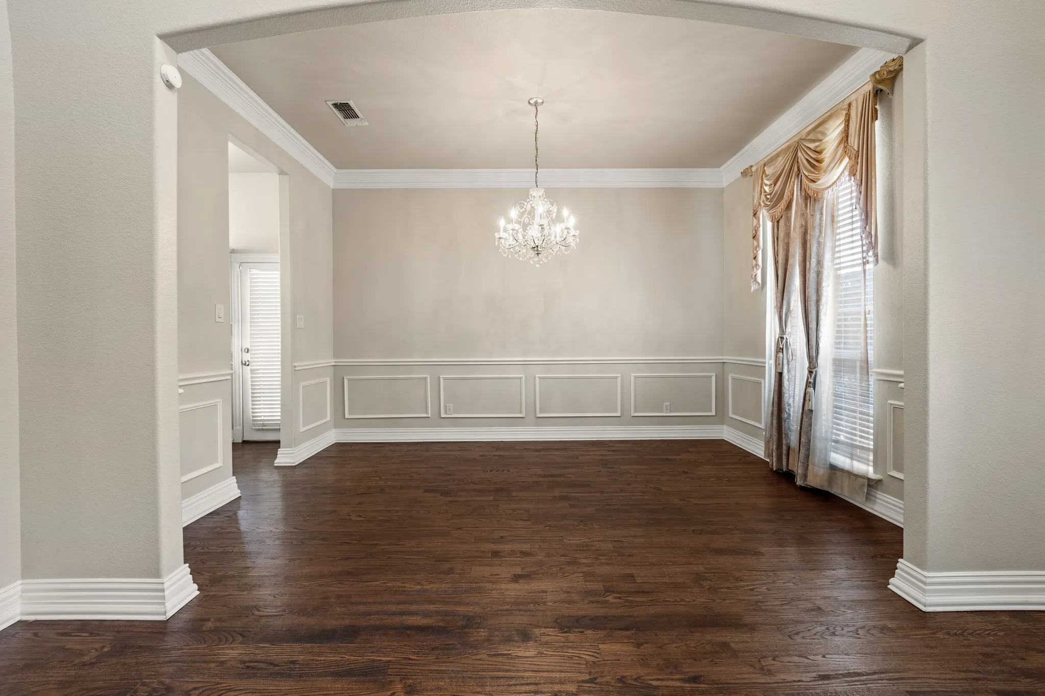 Unfurnished dining area featuring a healthy amount of sunlight, ornamental molding, dark wood-type flooring, and an inviting chandelier