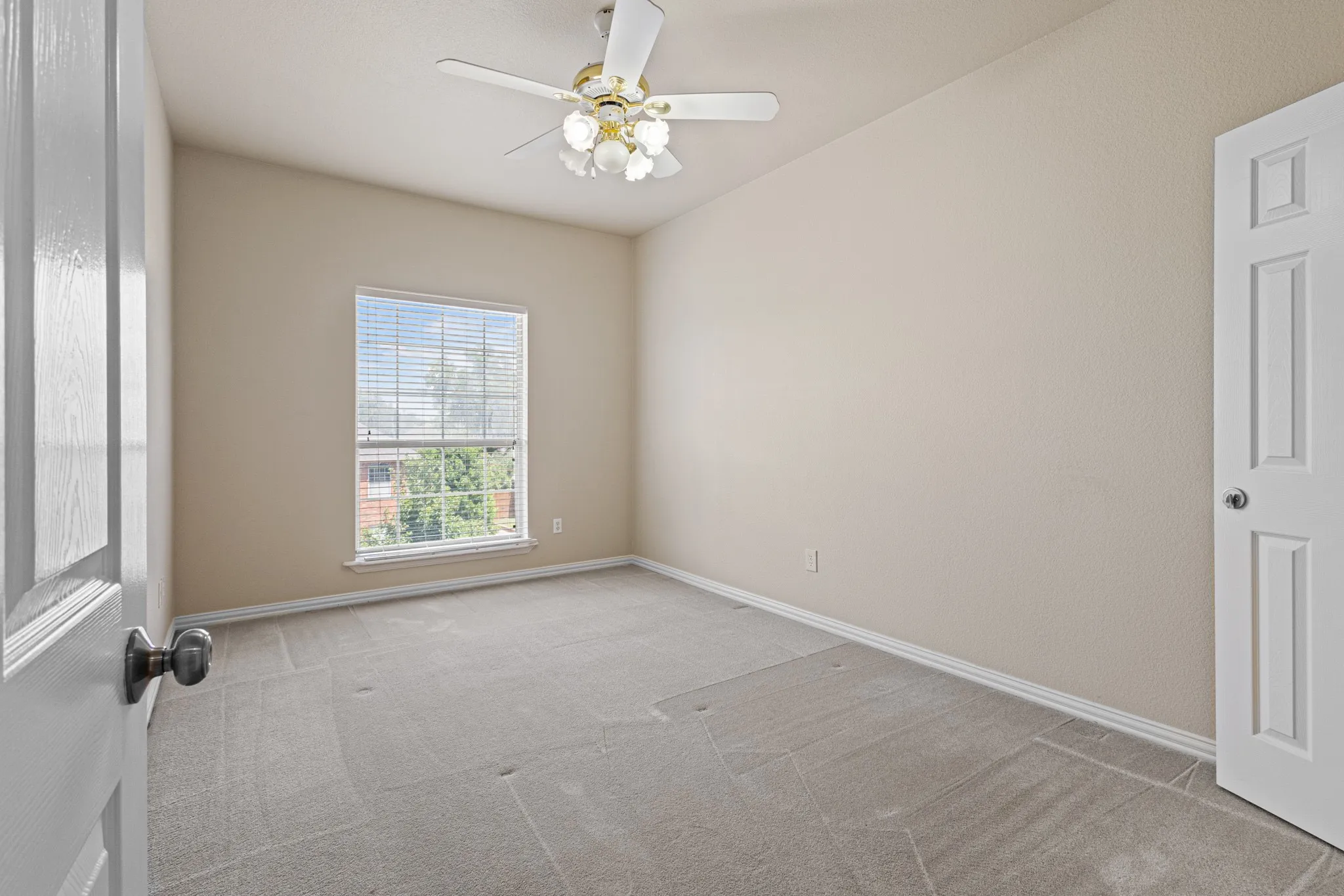 Carpeted spare room featuring ceiling fan