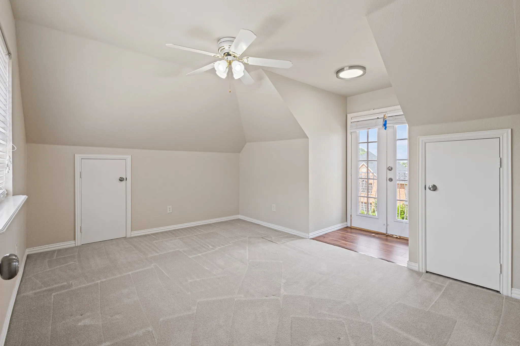Additional living space featuring ceiling fan, vaulted ceiling, and light colored carpet