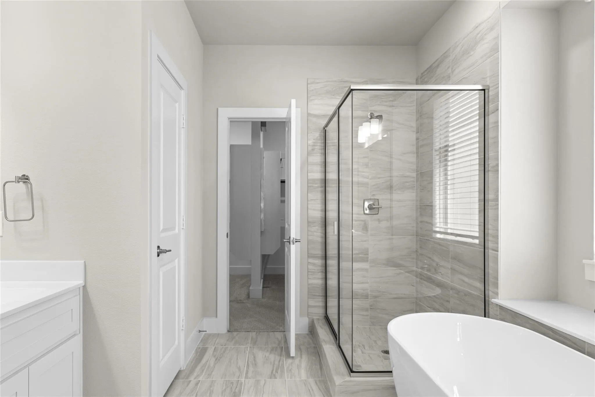 Modern bathroom featuring a freestanding soaking tub, glass-enclosed shower with tile surround, and a vanity with a white countertop
