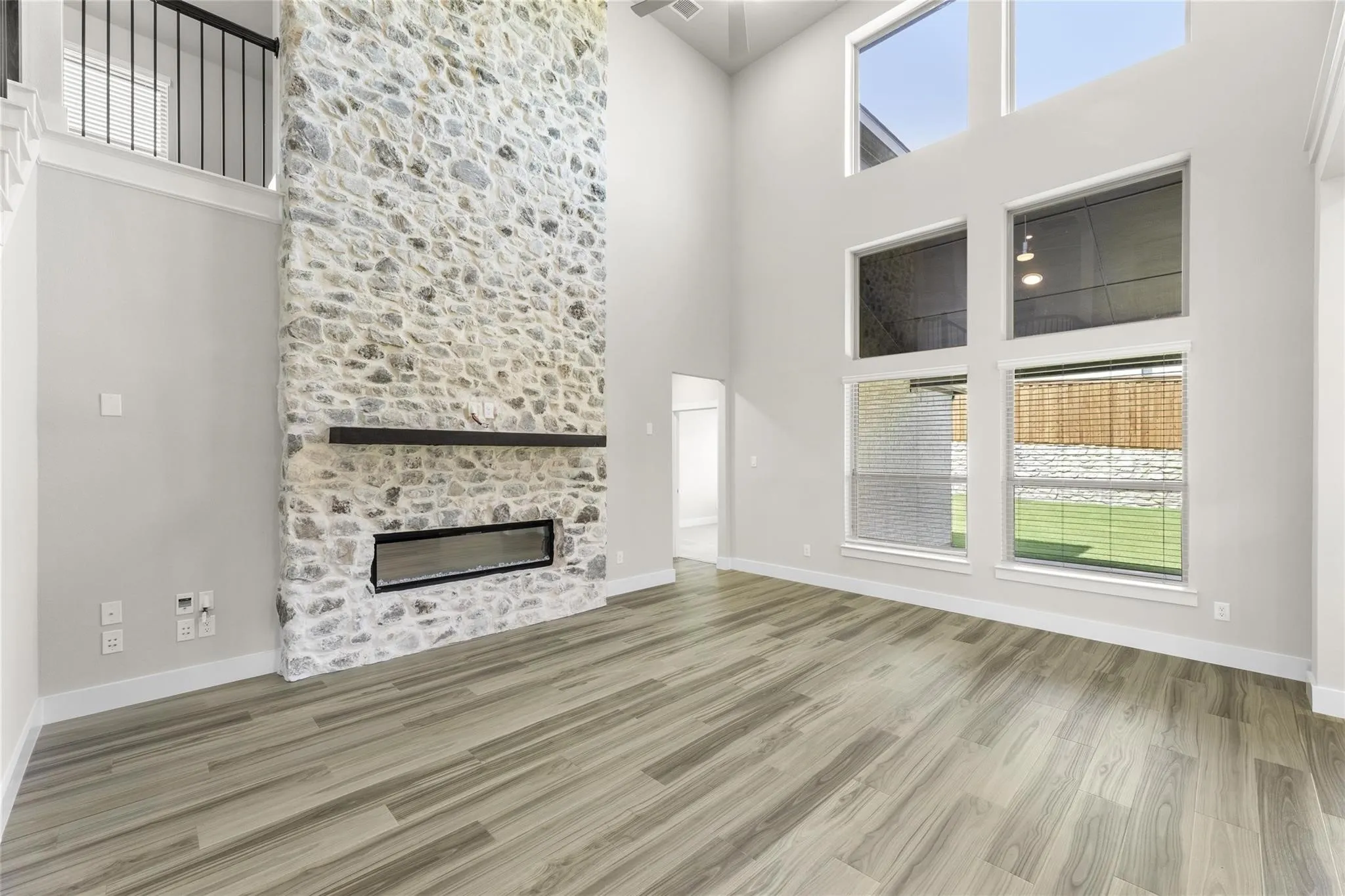 Double-height living space featuring a floor-to-ceiling stone fireplace with a modern linear insert and wood mantel
