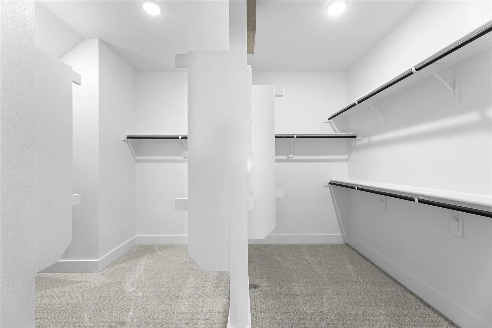 Walk-in closet featuring light gray carpeting, white walls, multiple shelving units, and recessed lighting