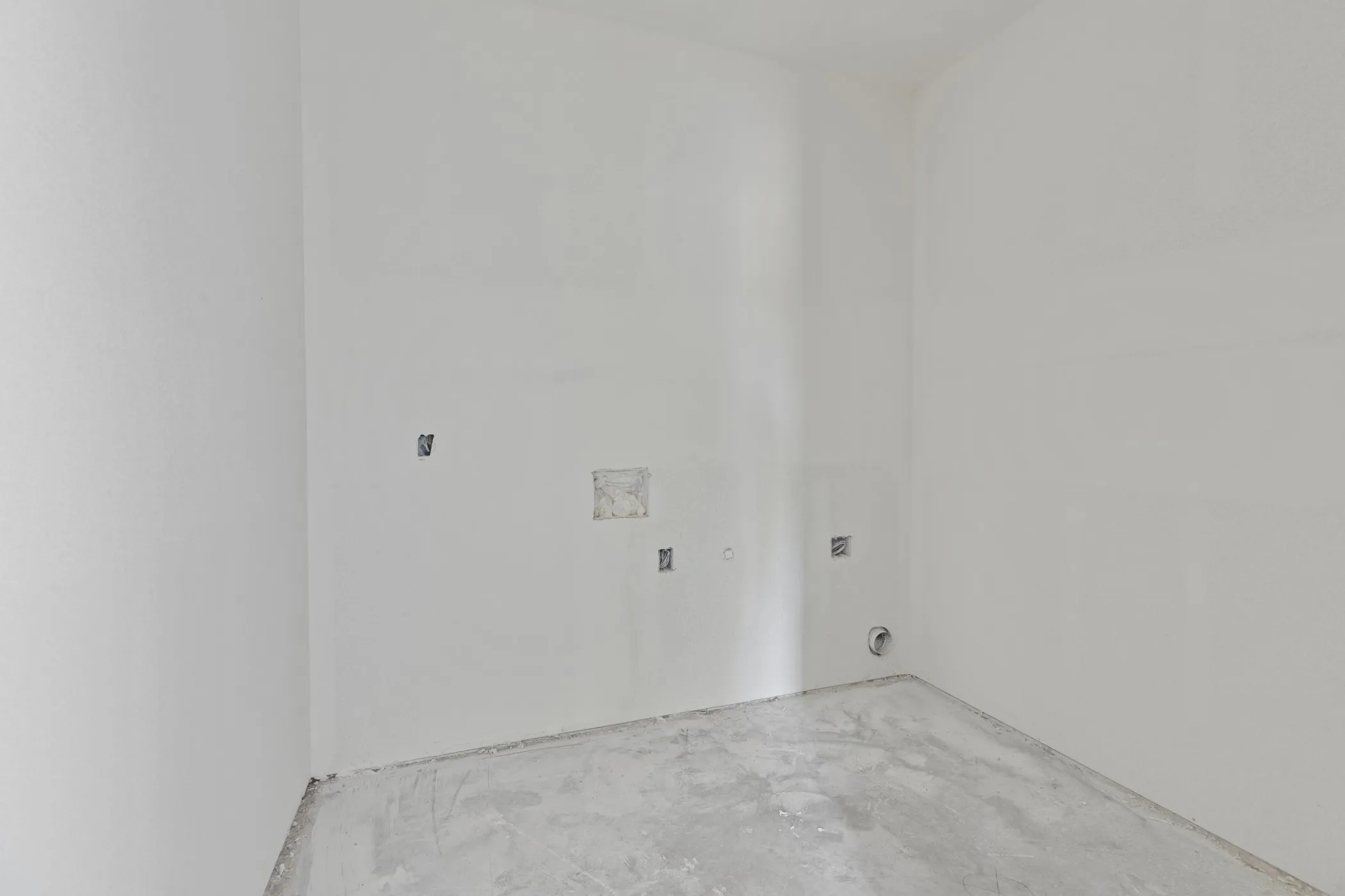 Unfinished room featuring white walls, concrete flooring, and visible electrical outlets