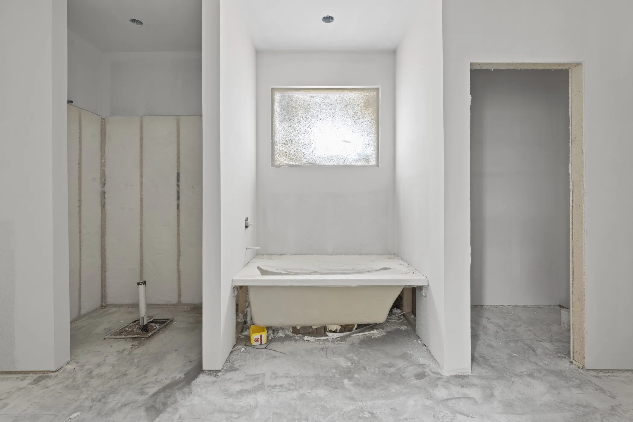 Bathroom under construction featuring a built-in tub basin and an adjacent shower enclosure