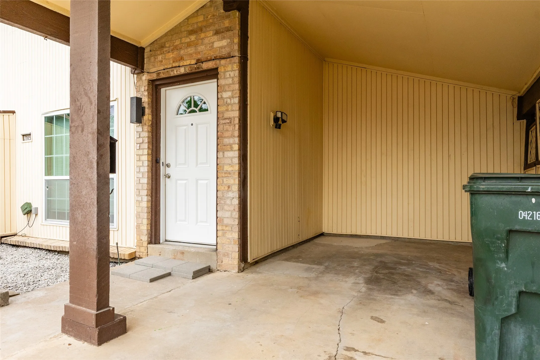 Covered entryway with a white paneled door featuring an arched window detail