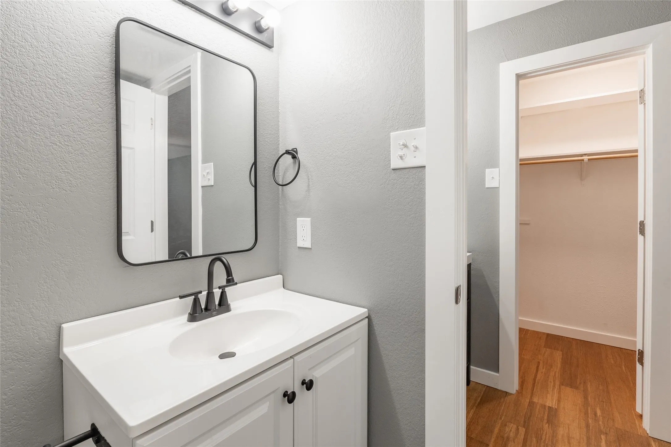 Bathroom vanity featuring a white countertop with an integrated sink and black hardware