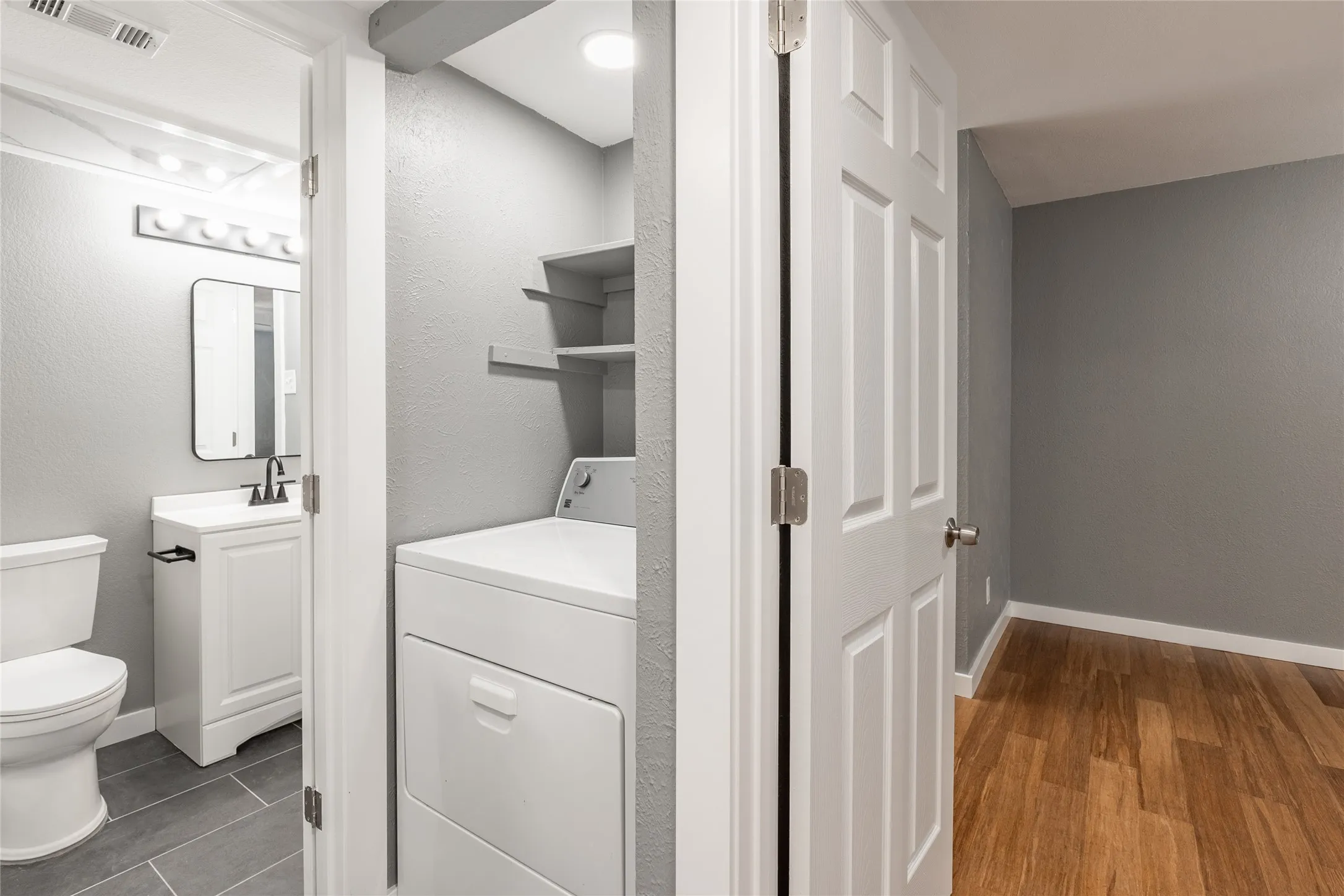 Bathroom with gray tile flooring, white vanity, and black faucet