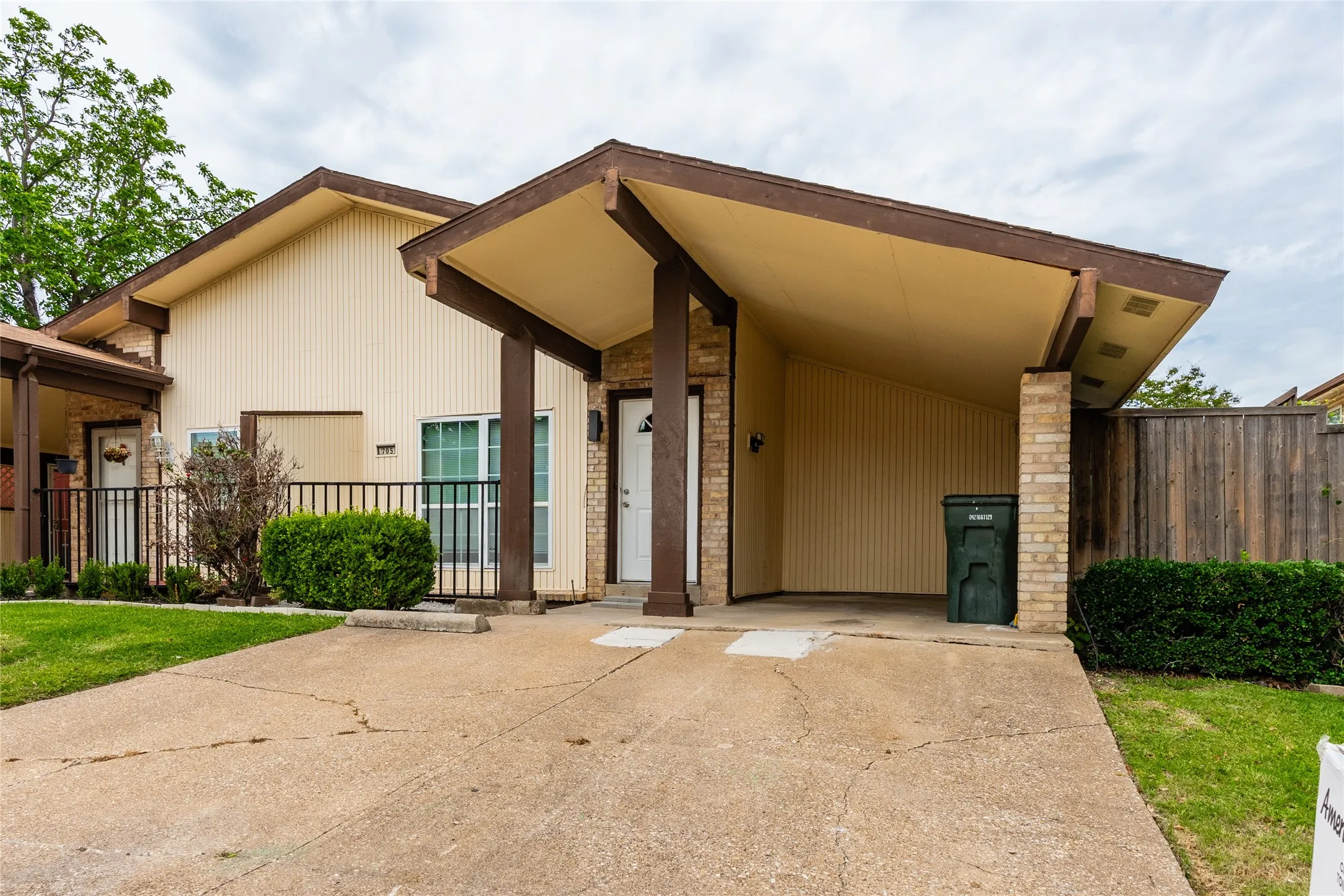 Front exterior featuring a covered carport, brick columns, and a private fenced patio