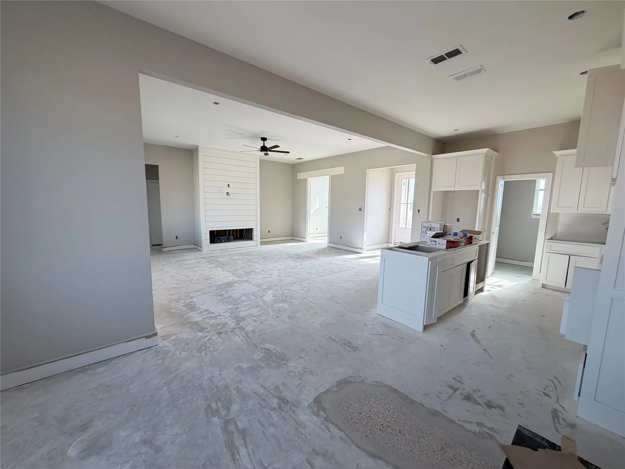 Open-concept layout featuring a white shiplap fireplace surround, recessed lighting, and a dark-toned ceiling fan