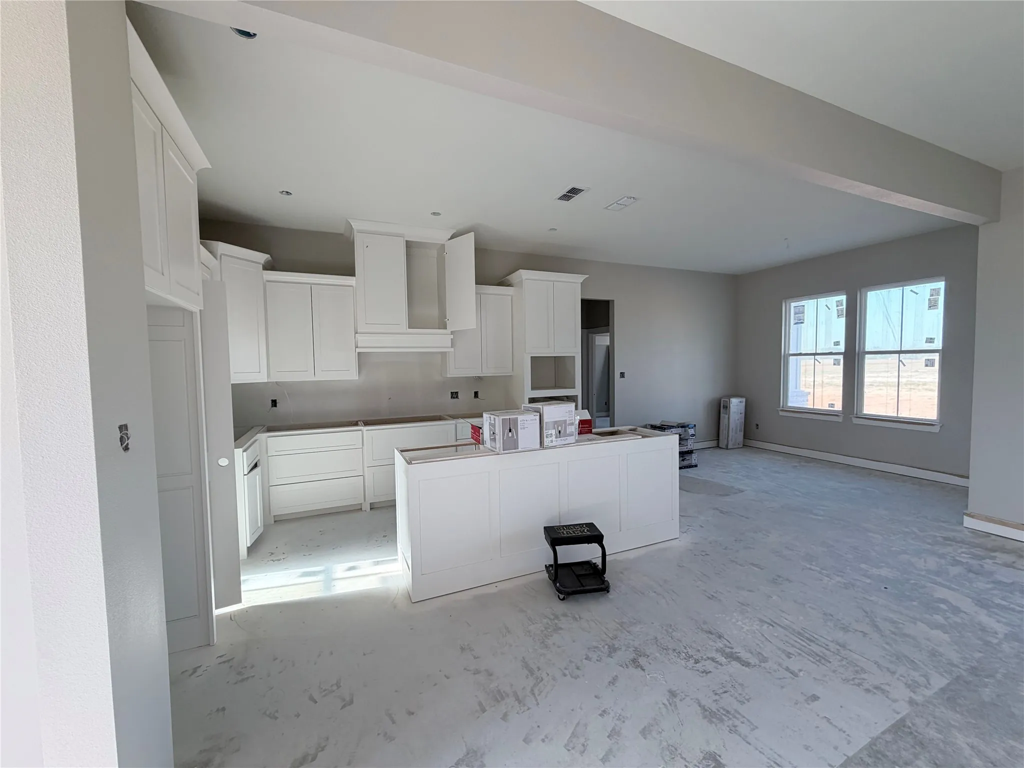 White shaker cabinetry, built-in kitchen island, multiple windows, recessed lighting, and a neutral color palette
