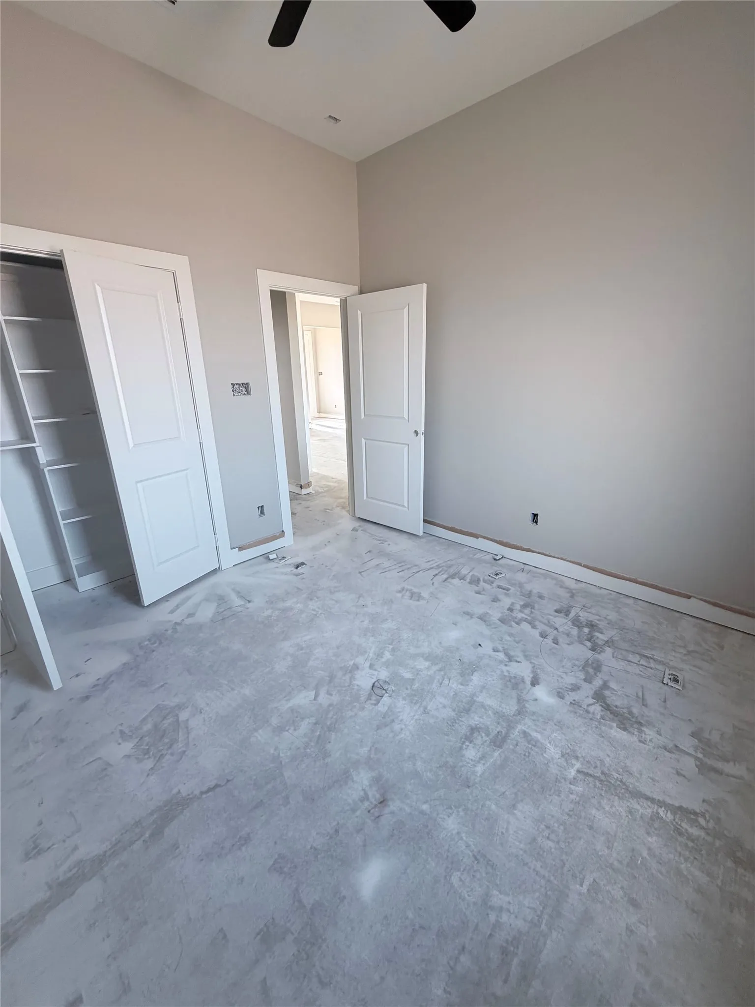 Vaulted ceiling, ceiling fan, neutral wall tones, white interior doors, built-in closet shelving