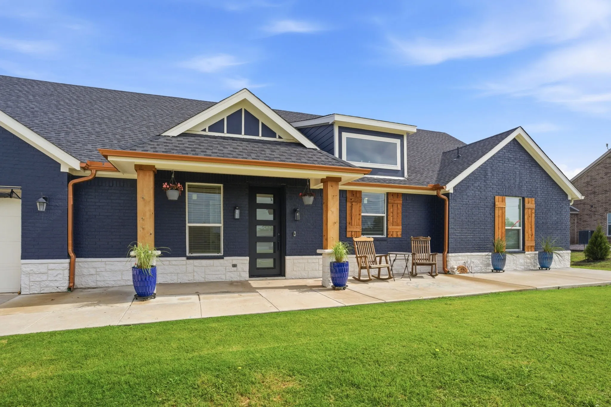 Stunning curb appeal sets this home apart ~ the painted exterior to the Texas stone skirting, cedar accents on the pillars & shutters, copper gutters, expanded concrete patio, pretty coach lights & twilight front door.