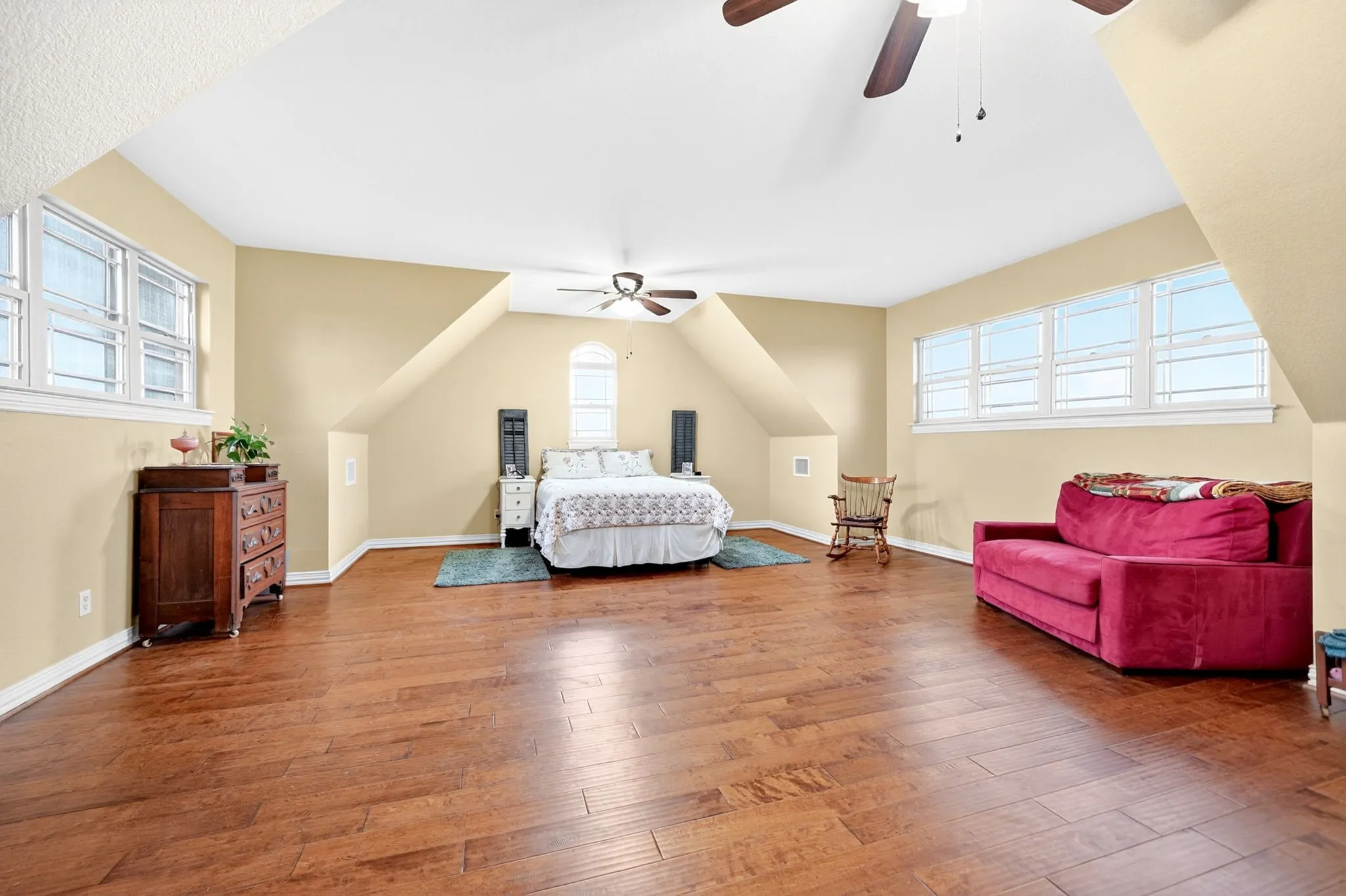 Spacious room featuring rich wood-finish flooring and multiple windows