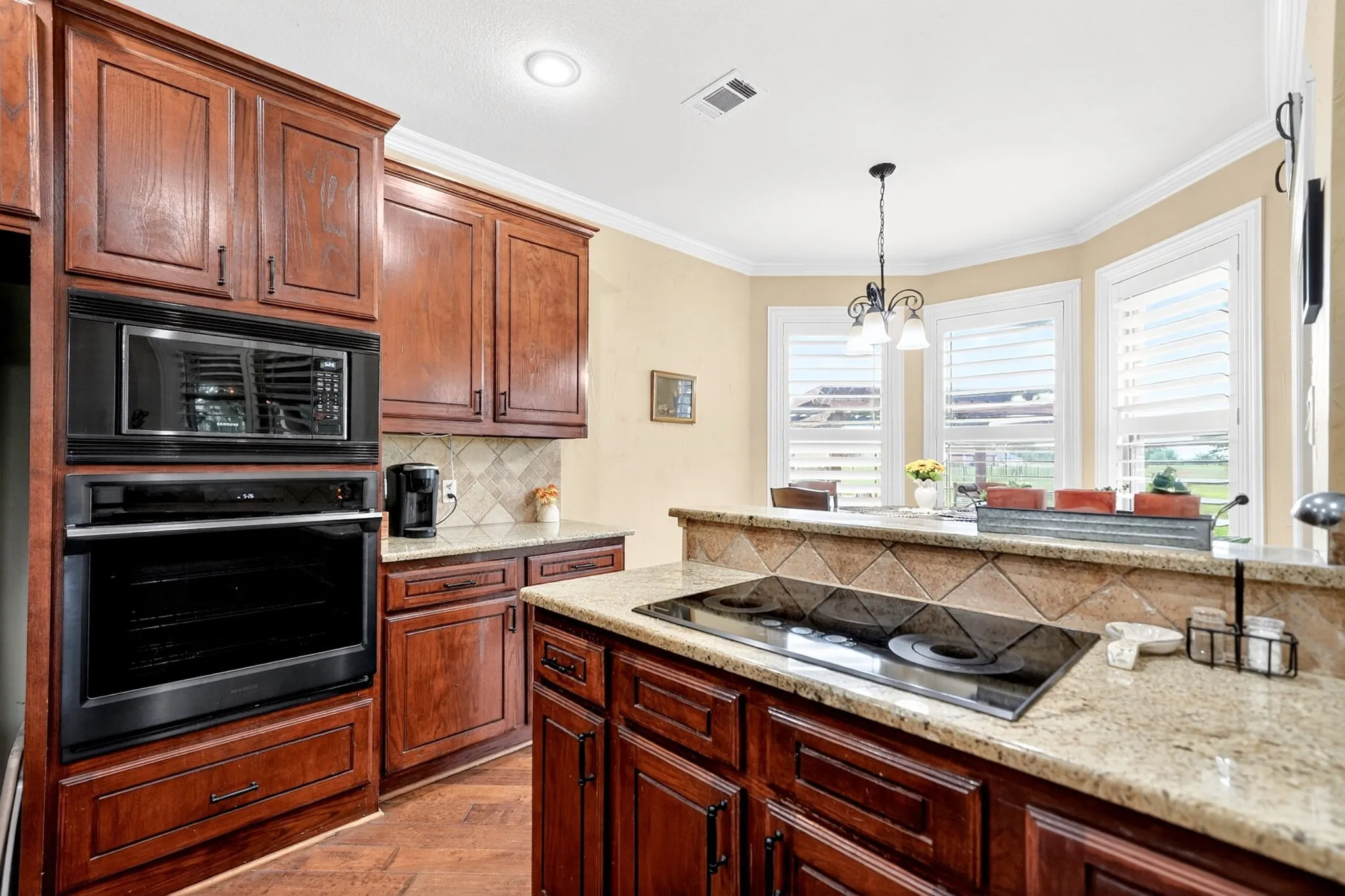 Kitchen featuring wood-finish cabinetry, granite countertops, an integrated cooktop, a built-in oven, and a built-in microwave