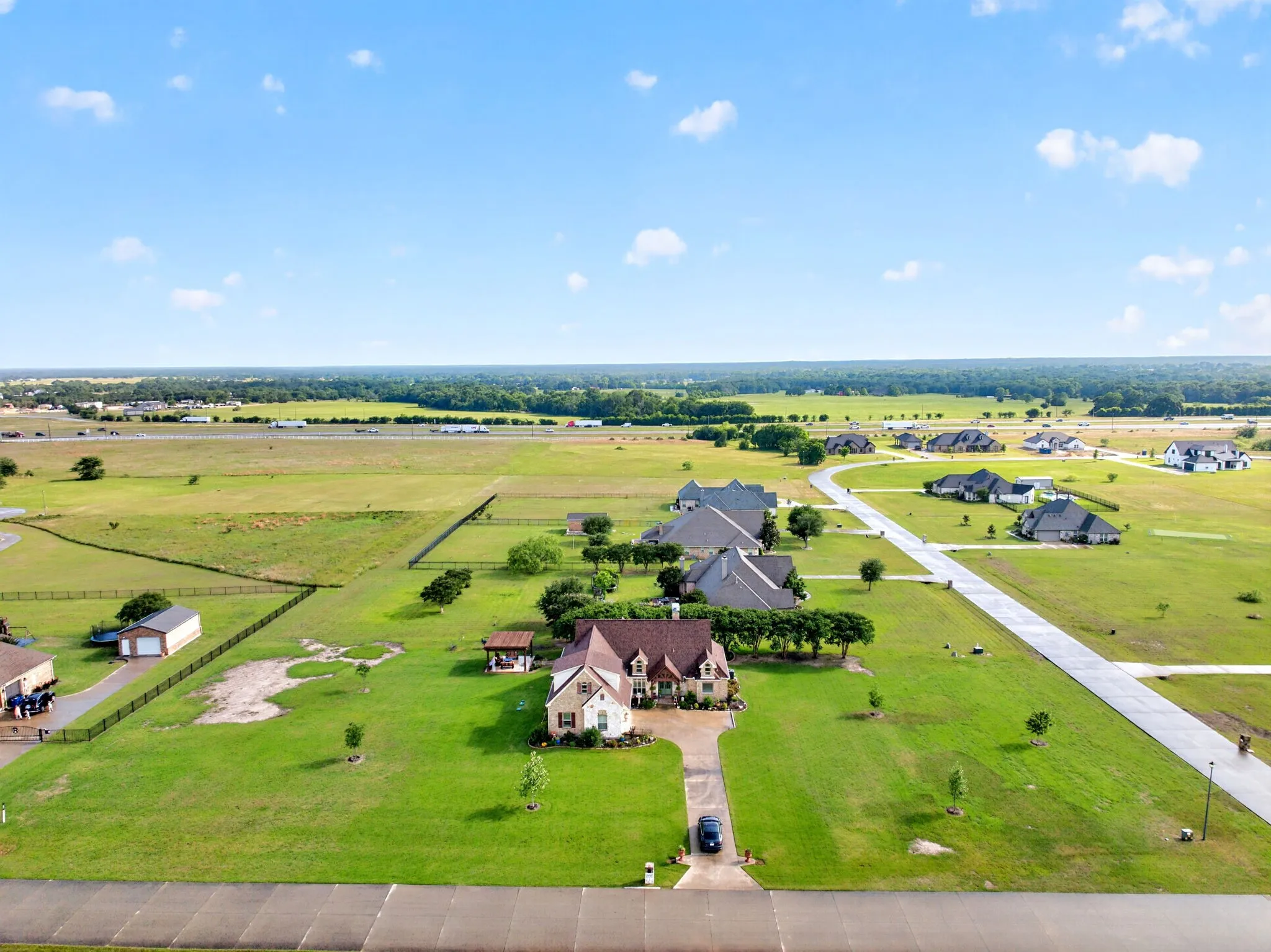 Aerial perspective showcasing a single-family residence with a stone and siding exterior, a dark shingle roof, and a paved driveway