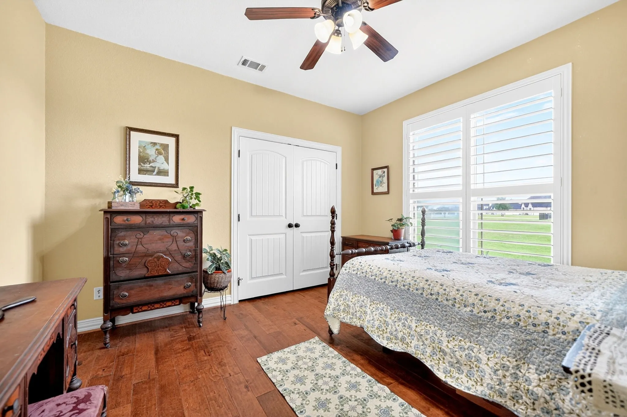 Wood-finish flooring throughout, featuring a large window with white louvered shutters