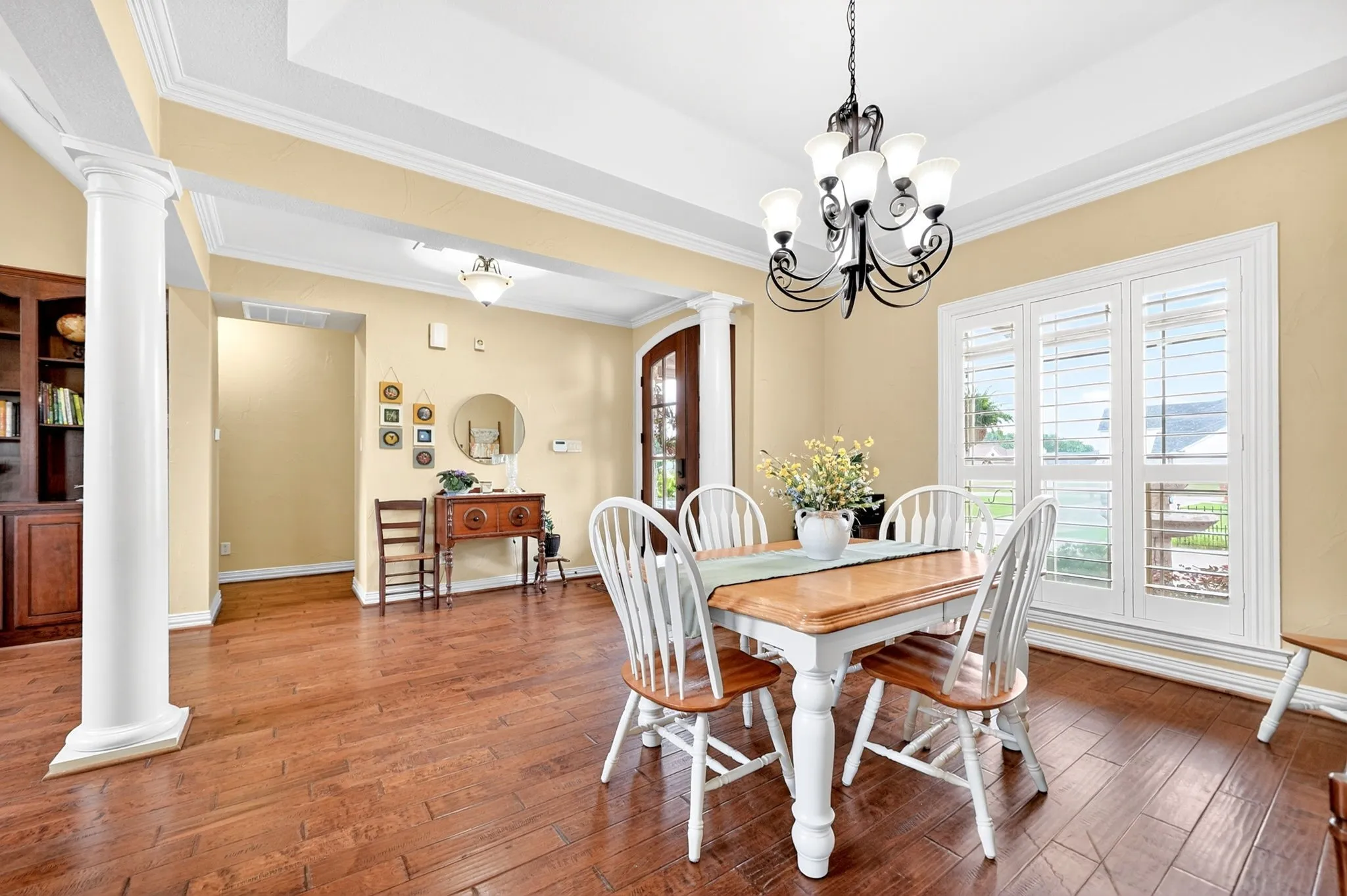 Dining area featuring wood-finish flooring, a tray ceiling, and a five-light chandelier