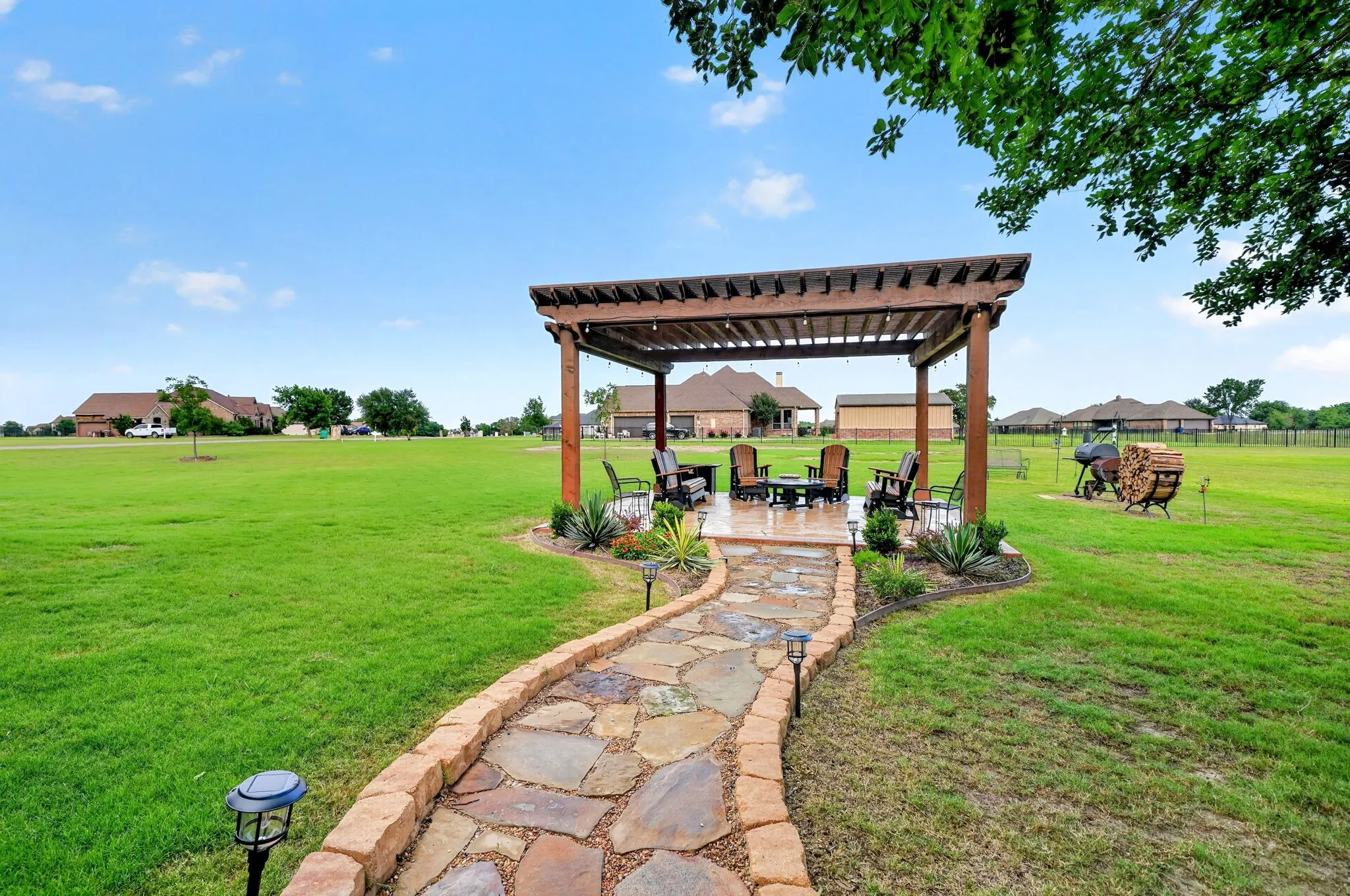 Expansive green lawn with a flagstone pathway leading to a wooden pergola
