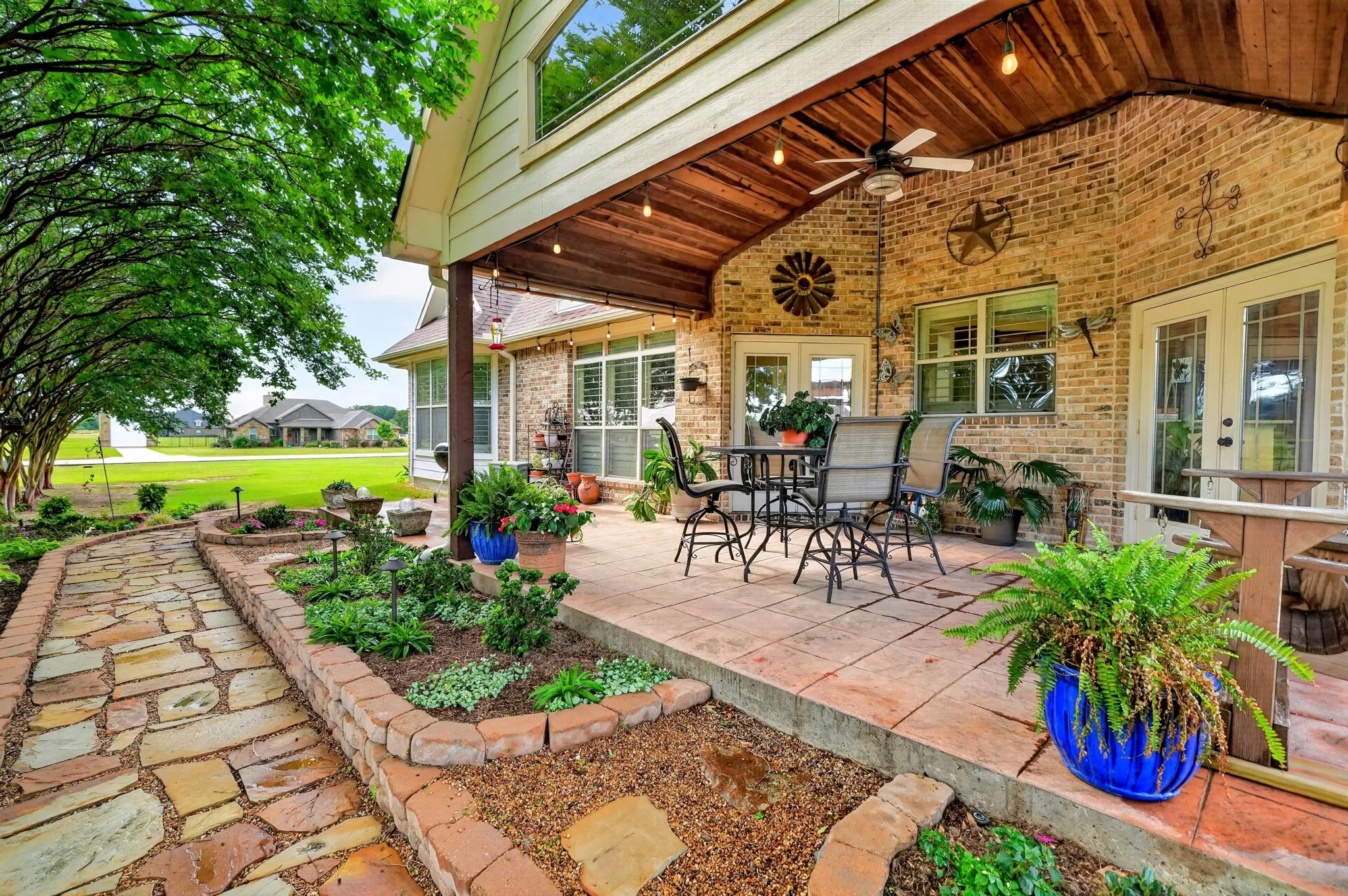 Covered patio featuring a wood-finish ceiling, exposed brick exterior, and a ceiling fan