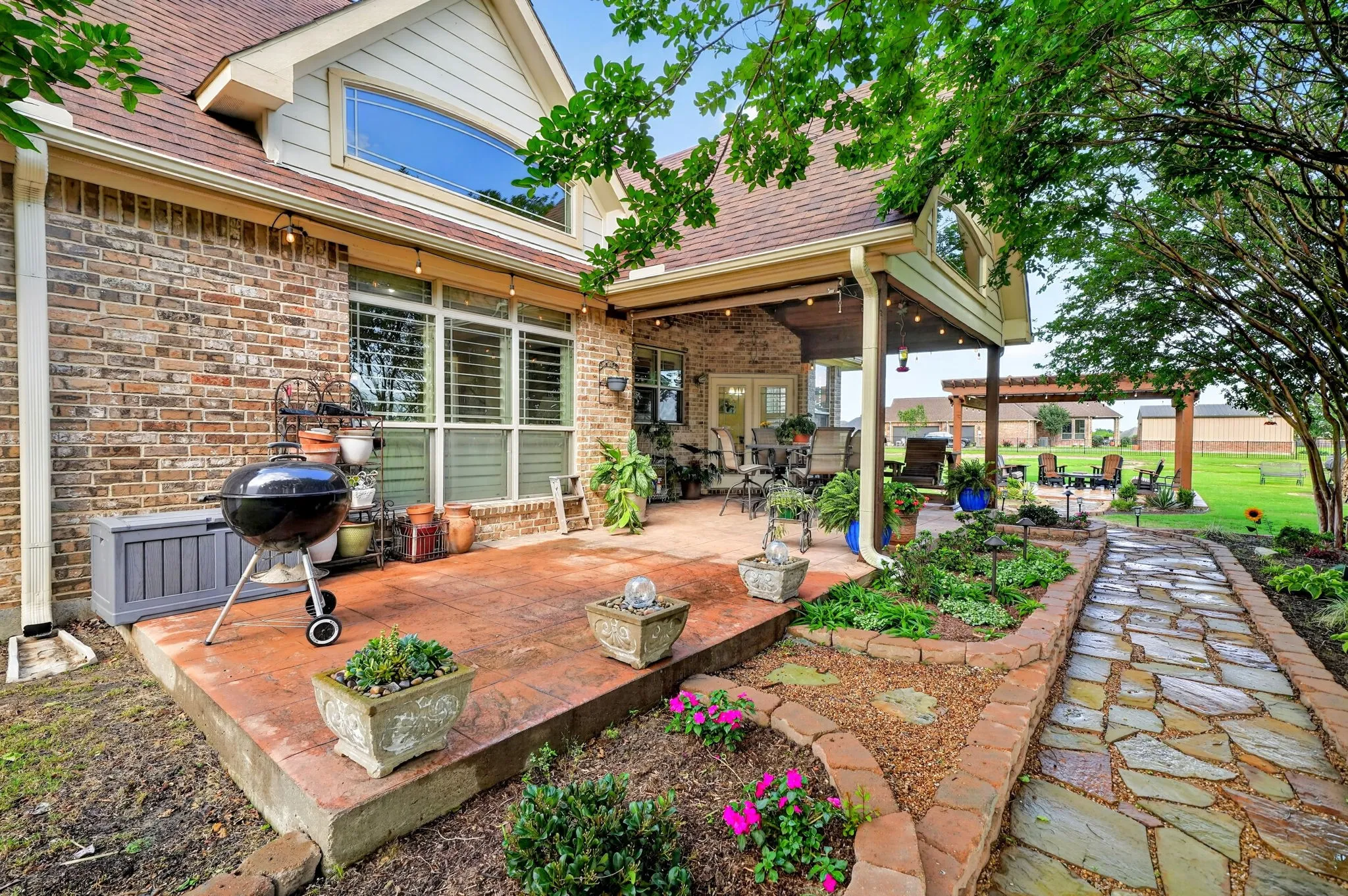 Expansive outdoor living area featuring a covered patio with recessed lighting, an extended stamped concrete patio, and a flagstone pathway