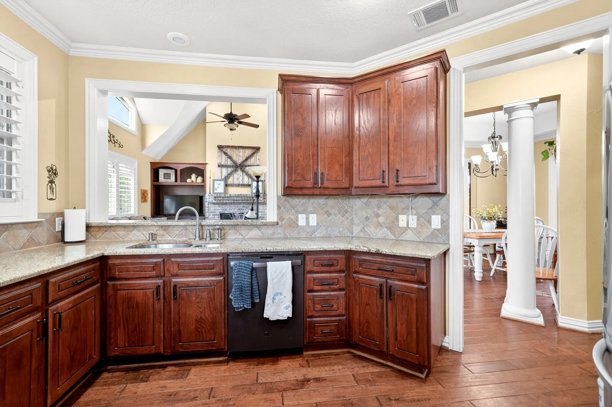 Kitchen featuring wood-finish flooring, granite countertops, and rich wood cabinetry