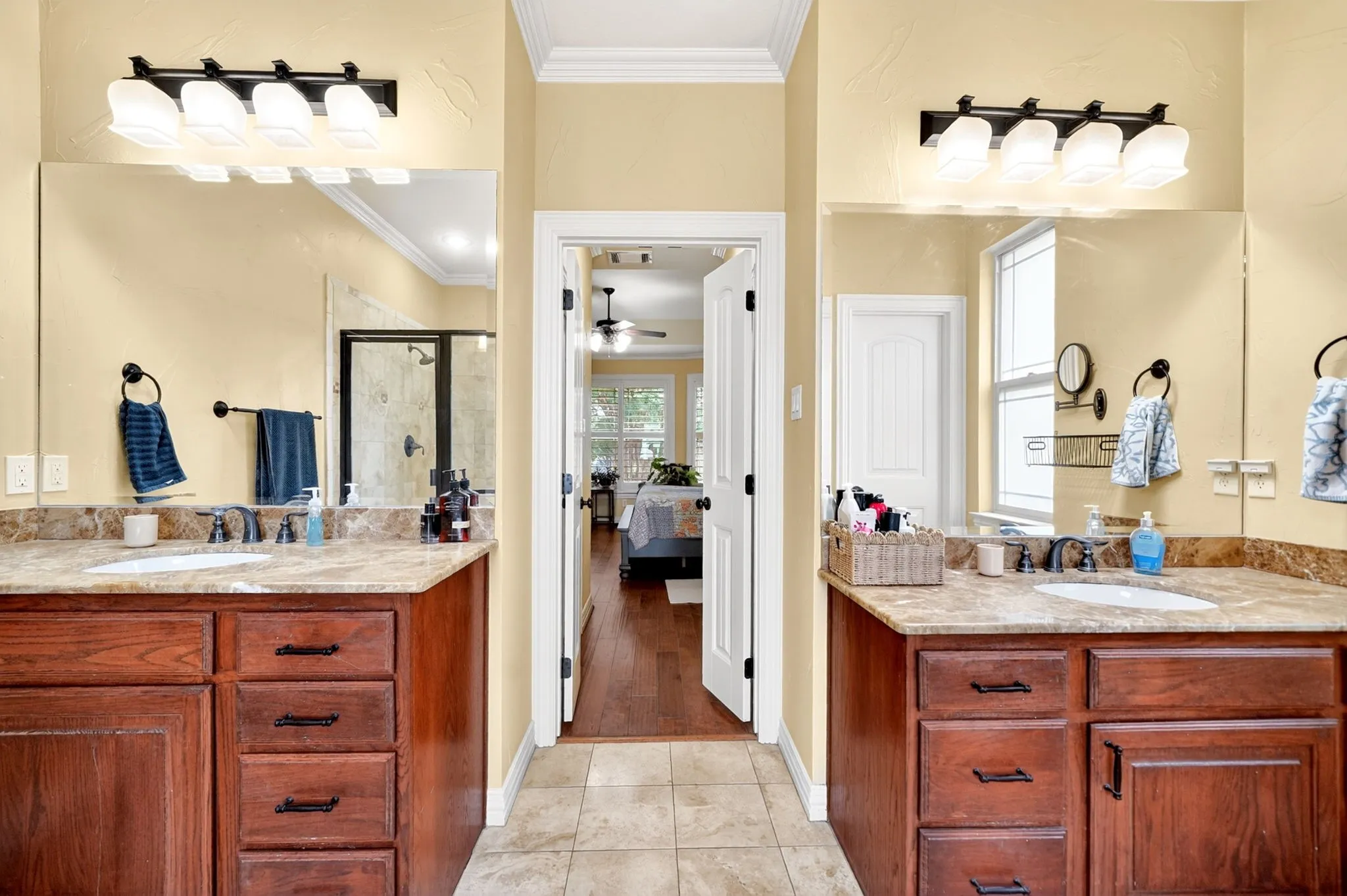 Dual vanity with wood-finish cabinetry, under-mount sinks, and stone countertops