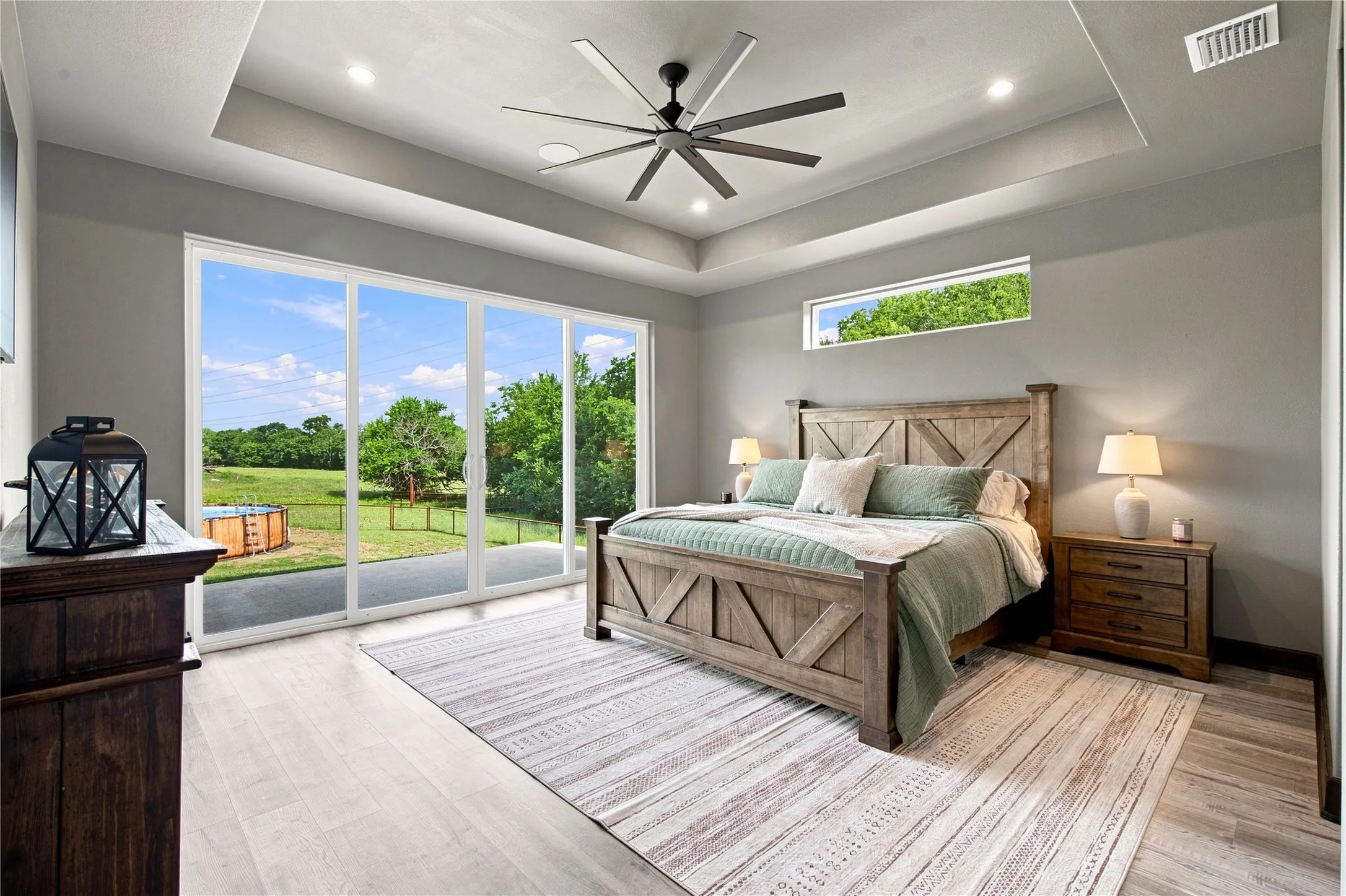 PRIMARY BEDROOM WITH SLIDING GLASS WALL GIVING AMPLE NATURAL LIGHT