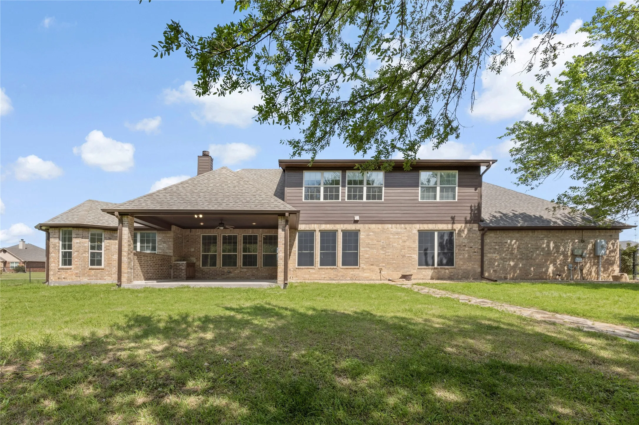 Expansive brick and siding exterior featuring a covered patio with recessed lighting and a ceiling fan