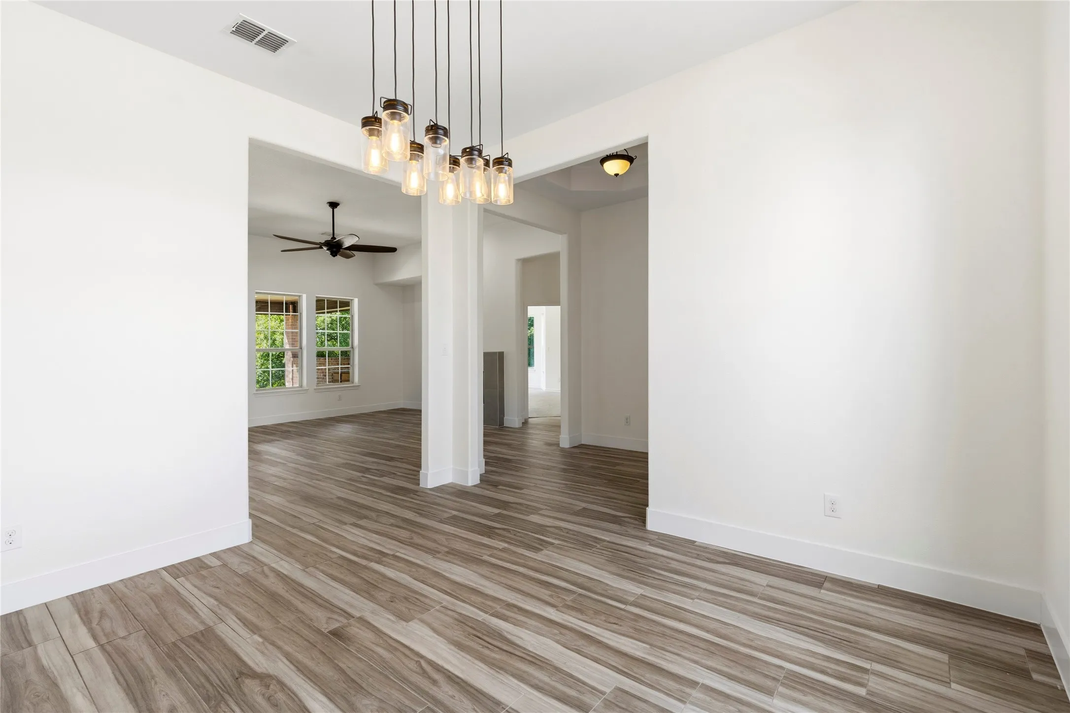 Open concept space featuring wood-finish flooring, a contemporary chandelier, recessed lighting, and a ceiling fan